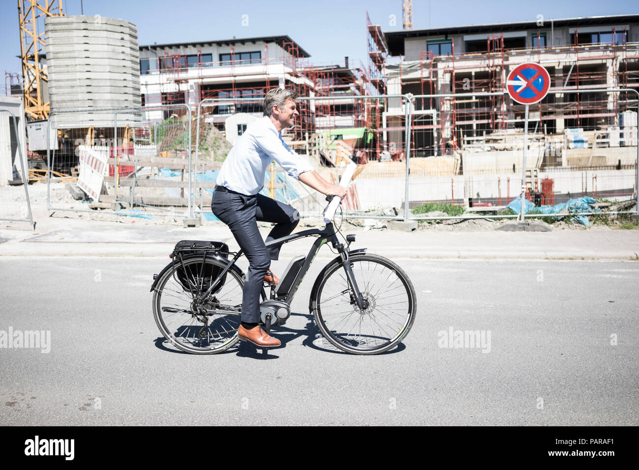 Lächelnde Menschen auf e-Bike Reiten entlang der Baustelle Stockfoto