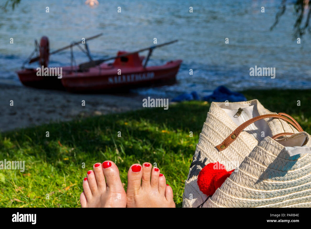 Chillen am See entspannt Konzept, Konzept, Konzept, sitzen im Gras, rot Zehennägel, Strandtasche, unplugged Konzept Stockfoto