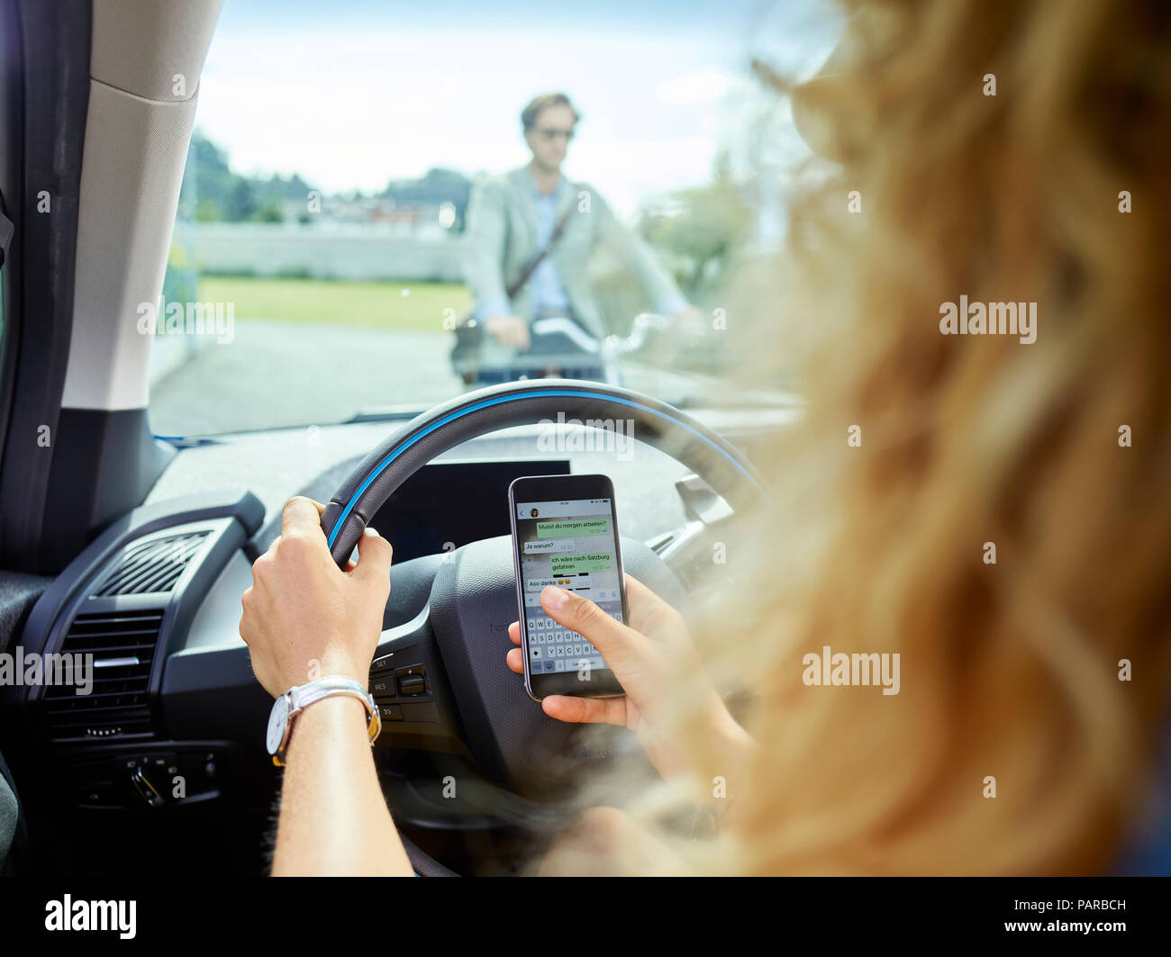 Junge Frau in elektrischen Auto SMS auf Handy Stockfoto
