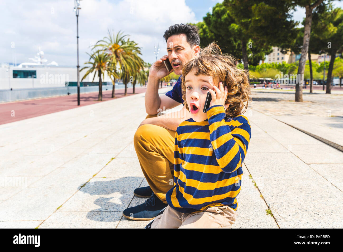 Spanien, Barcelona, Vater und Sohn, beide mit einem Smartphone Stockfoto