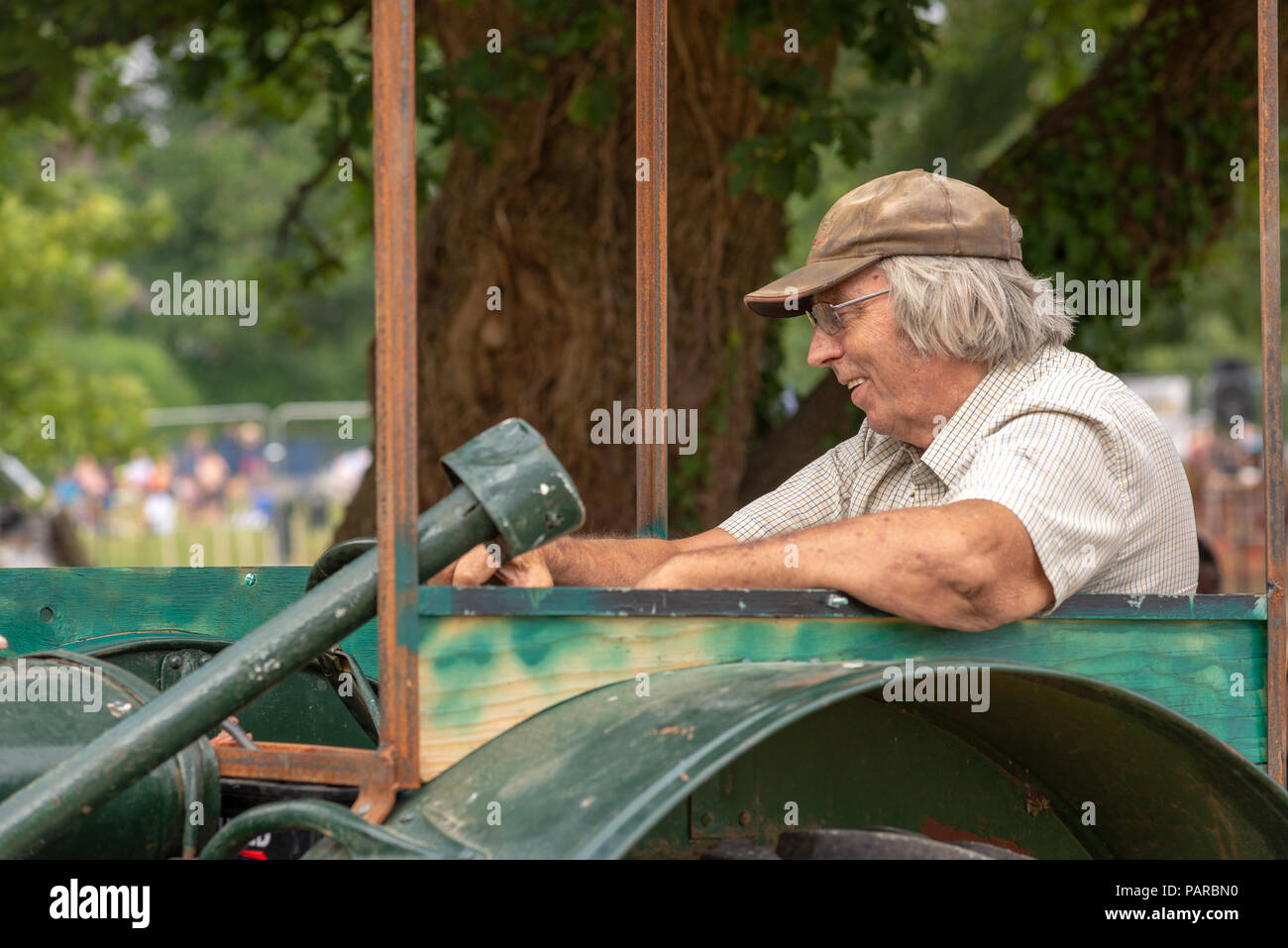 Ältere Mann, der ein Vintage Traktor auf einem Sommerfestival in Hampshire, Großbritannien Stockfoto