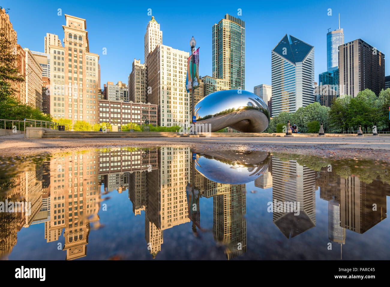 CHICAGO - Illinois: Mai 9, 2018: Cloud Gate in Millennium Park spiegeln sich in einer regen Pfütze mit klarem Himmel. Stockfoto