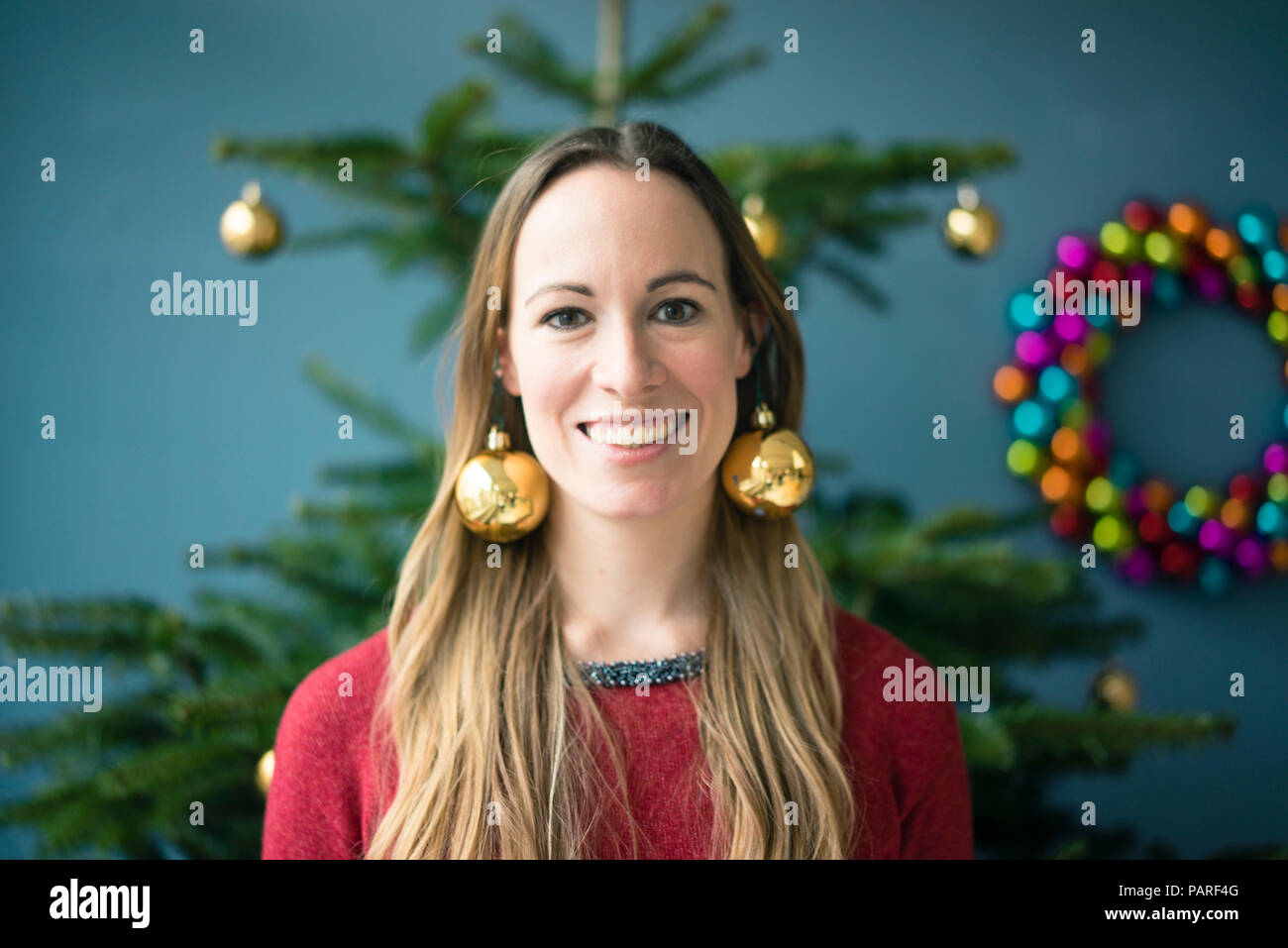 Portrait von lächelnden Frau mit goldenen Christbaumkugeln Ohrringe Stockfoto