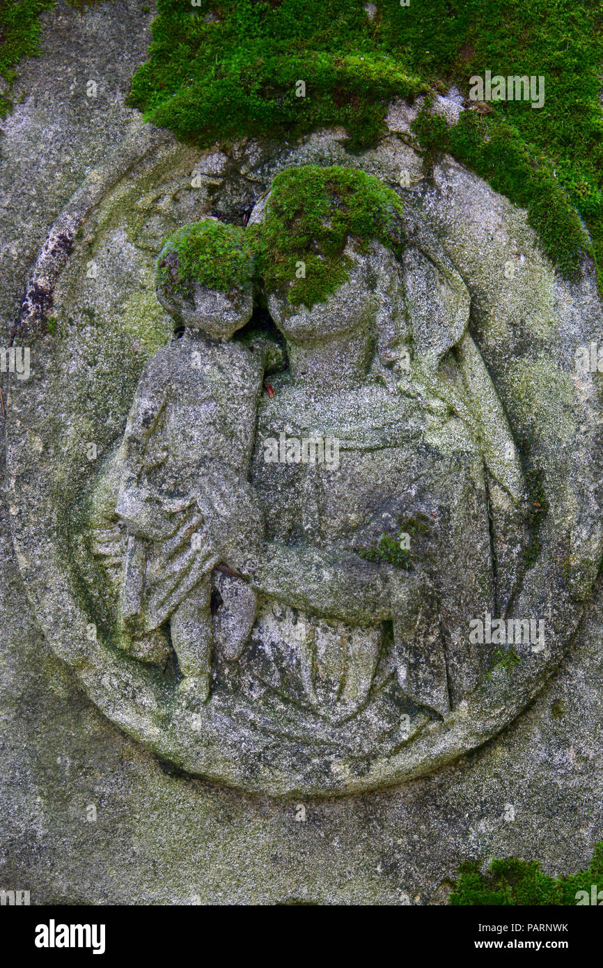 Ein Moos bedeckt Relief der Hl. Maria auf einem Grabstein auf einem verlassenen Friedhof in Wien Stockfoto