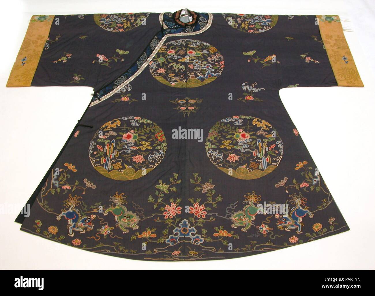 Woman's Informelle Robe mit Garten Roundels. Kultur: China. Abmessungen: 43 x 52 in. (109,22 x 132.08 cm). Datum: Anfang des 18. Jahrhunderts. Die roundels auf diesem Gewand zeigen Garten Felsen mit Blumen, Obst, und verheissungsvollen Elemente wie der endlose Knoten und Fledermäuse (Fu, ein Homophone mit dem Wort für Glück). Am unteren Rand des Kleidungsstücks, zwei Paare der Chinesischen Löwen hüpfen mit Beribboned Kugeln in einen blühenden Garten. Museum: Metropolitan Museum of Art, New York, USA. Stockfoto