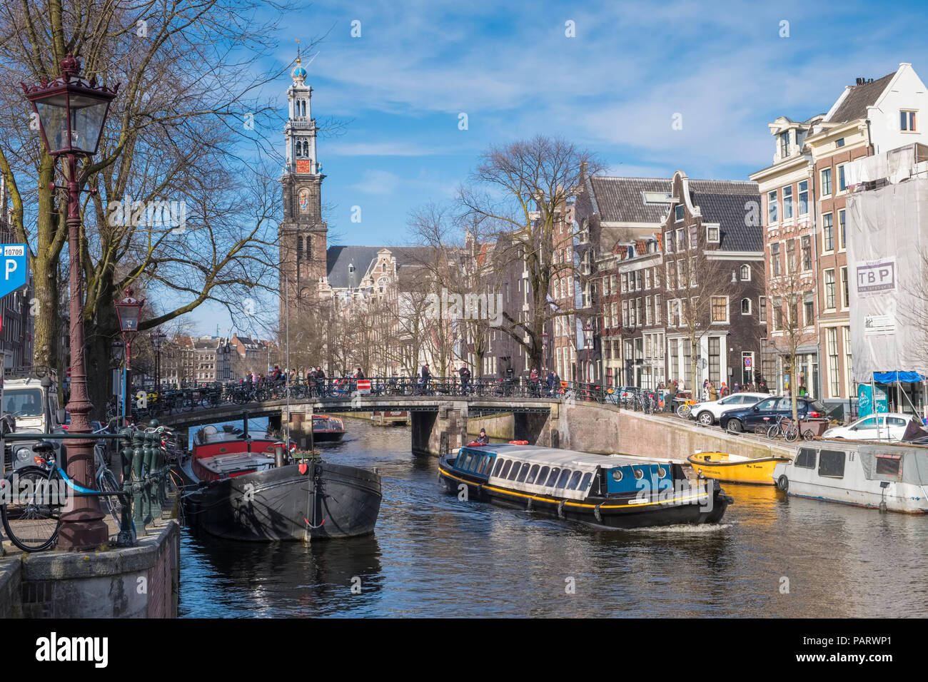 Viele Fahrräder auf einer Brücke mit Blick auf eine Gracht in Amsterdam, Niederlande, Europa mit einem Boot unter Segeln Stockfoto