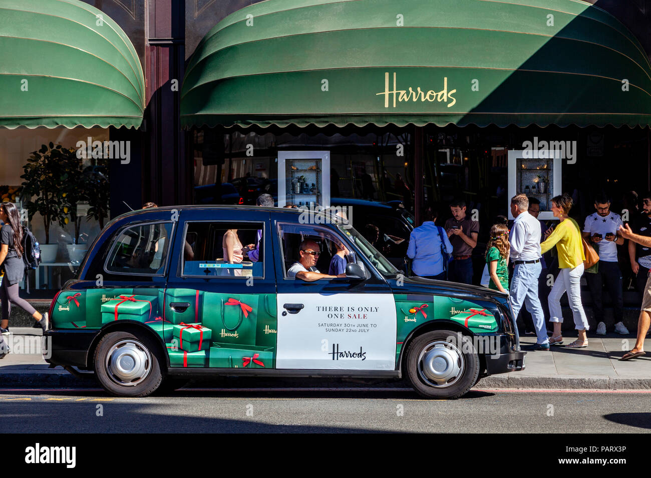 Ein traditionelles Londoner Taxi mit Harrods Branding außerhalb Kaufhaus Harrods, Brompton Road, Knightsbridge, London, England Stockfoto