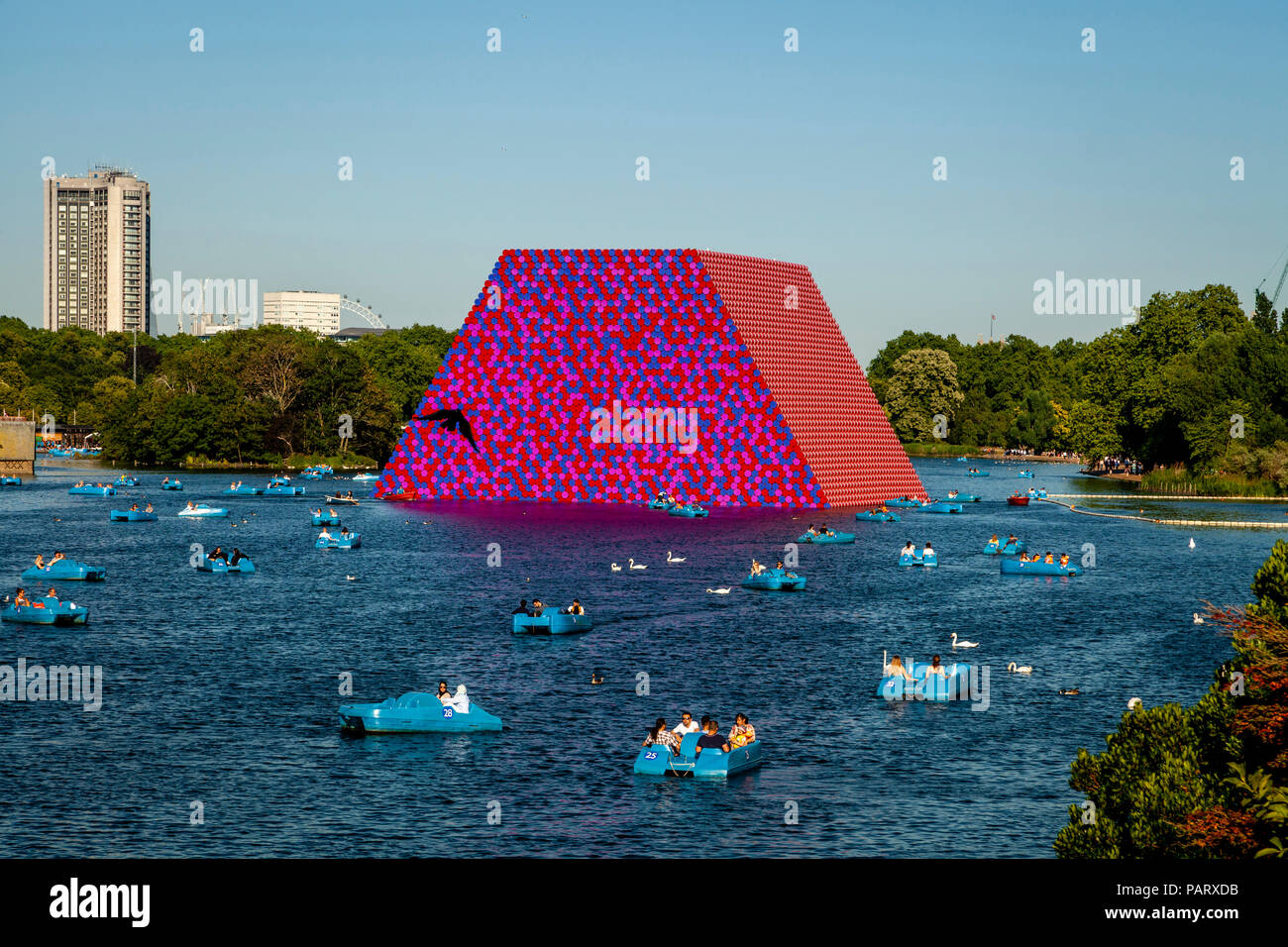 Menschen in Tretboote auf dem Serpentine mit "Die mastaba "Schwebende Skulptur im Hintergrund, Hyde Park, London, England Stockfoto