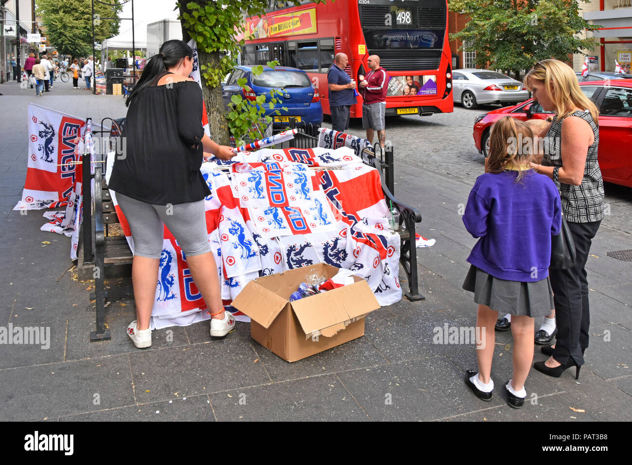 Mama & Kinder Straßenszene in Shopping High Street kaufen England Fußball Team Souvenir am Tag des WM-Spiels Brentwood Essex England UK Abschaltdruck Stockfoto