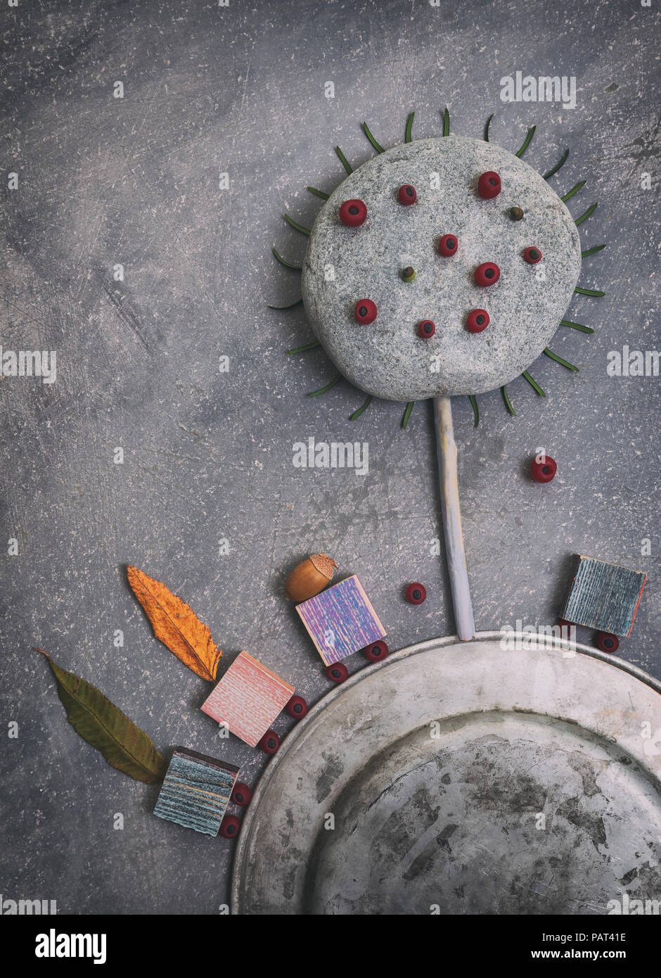 Kreative herbstliche Arrangement aus verschiedenen Objekten: Blätter, Eicheln, runden Stein und Beeren auf Grau scratchy Hintergrund Stockfoto