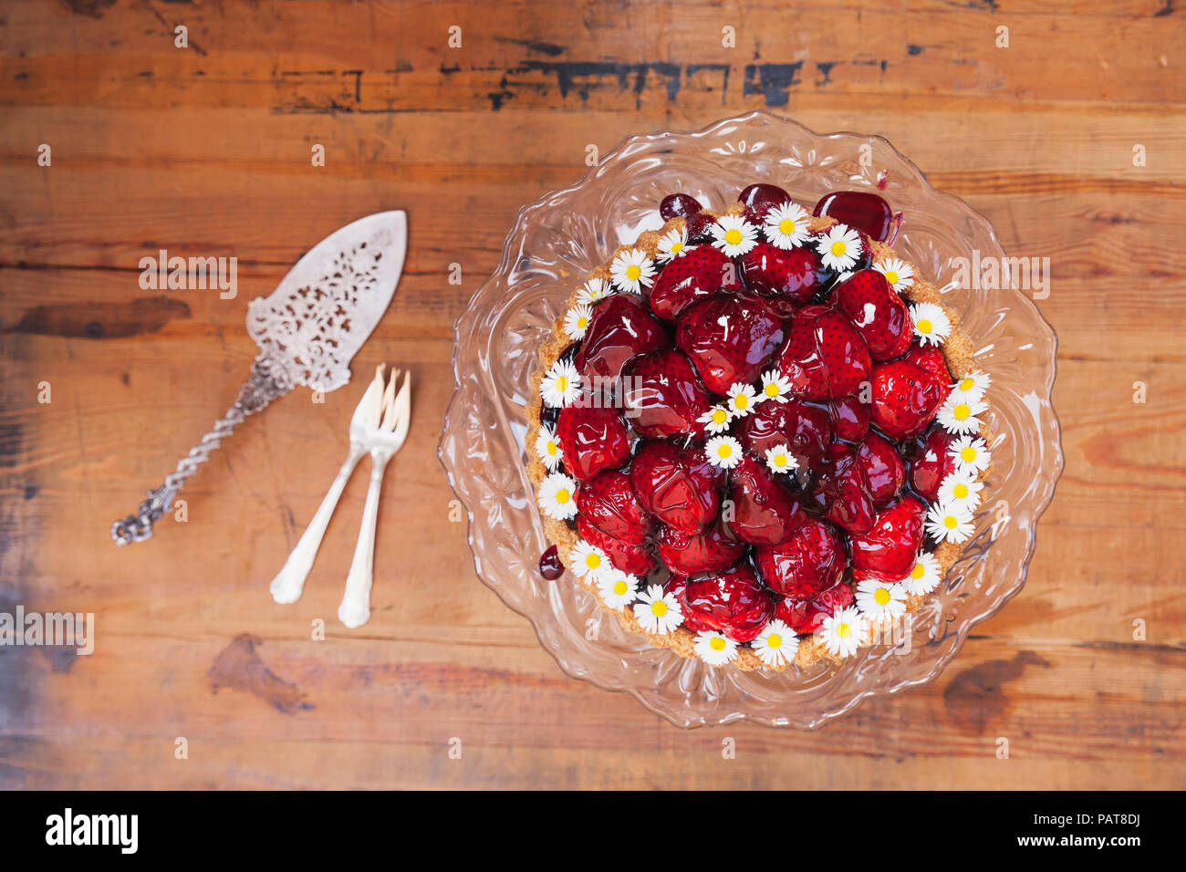 Hausgemachte Erdbeertorte mit Traubensaft rot Glasur und daisy flower Dekoration auf alten Kuchen stand Stockfoto