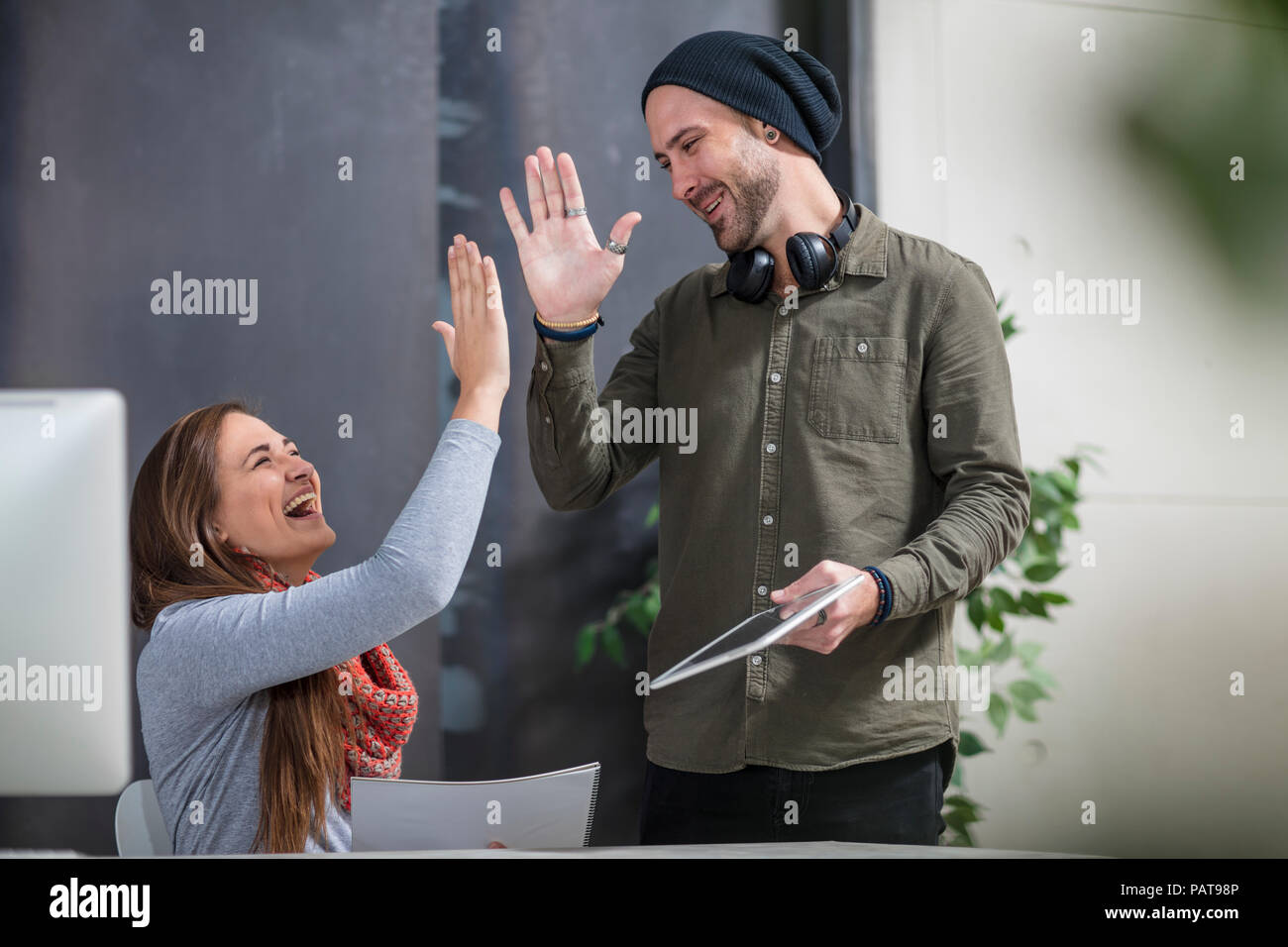 Zwei Kollegen eine hohe fünf am Schreibtisch im Büro Stockfoto