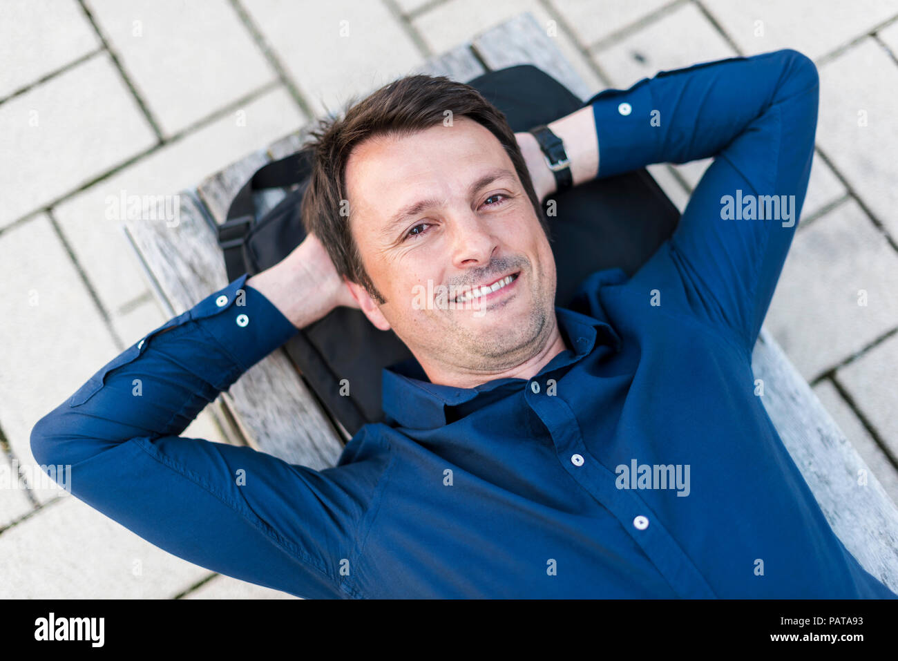 Portrait von lächelnden Geschäftsmann auf der Werkbank liegen im Freien Stockfoto