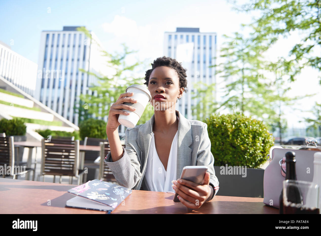 Portrait der Unternehmerin mit Handy trinken Kaffee im Straßencafé Stockfoto
