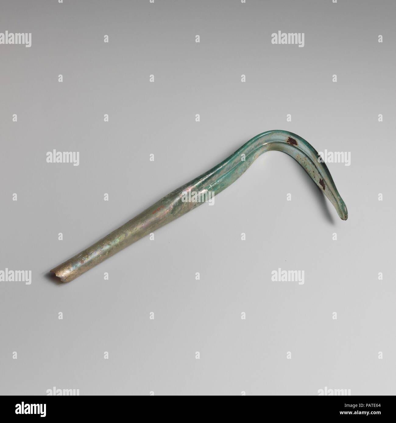 Glas strigil (Abstreifer). Kultur: Roman. Abmessungen: Länge 7 15/16 in. (20,2 cm), Breite 1 1/16-in. (2,7 cm). Datum: 3.-4. Jh. N.CHR.. Transluzent blau grün. Griff in der Form eines Hohlzylinders, leicht nach unten erweitert; die geschwungene Klinge oder scrapper Abschnitt hat Flachbild nachgerüstet worden mit einer tiefen Gedankenstrich, der seine Länge auf der oberen Seite, endet in einer abgerundeten Spitze. Oben Griff gebrochen und fehlt; Nadelstich und kleine längliche blasen; Mattierung, Lochfraß und irisierenden Verwitterung, mit etwas Erde Verkrustung und dicker Überstehen auf Interieur. Eine kleine Anzahl von Glas strigi Stockfoto