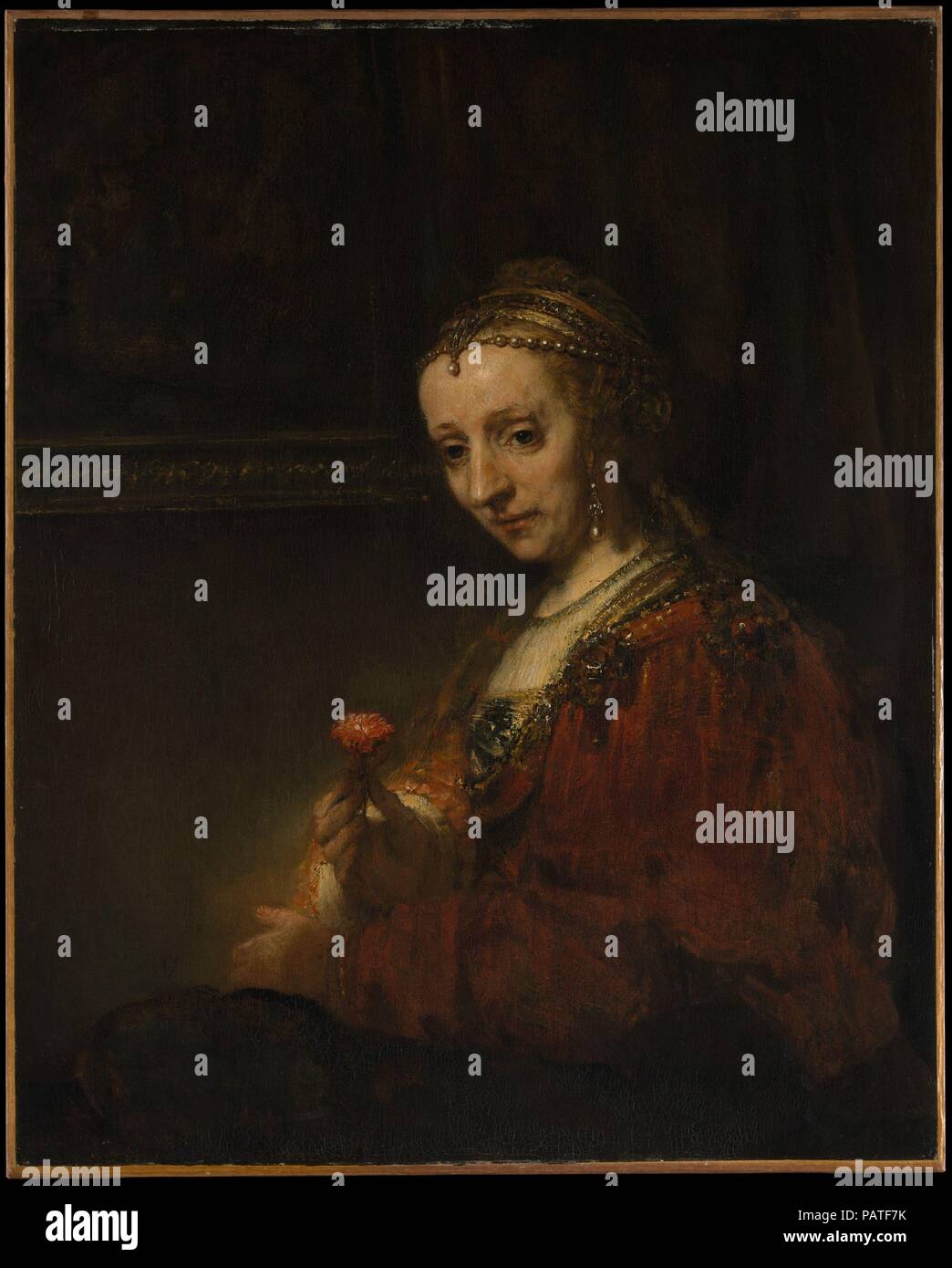 Frau mit einem Rosa. Artist: Rembrandt (Rembrandt van Rijn) (Niederländisch, Leiden 1606-1669 Amsterdam). Abmessungen: 36 1/4 x 29 3/8 in. (92,1 x 74,6 cm). Termin: Anfang 1660 s. Das Tragen eines romantisch veraltete Kostüm und exotischen Schmuck, die Frau hält eine rosa, oder Nelke, Symbol der Liebe und der Ehe. Wenn der Sitter in den Anhänger Portrait, <i>Mann mit einem Vergrößerungsglas</i> (14.40.621) ist Pieter Haringh, dann bescheiden lächelnde Frau ist seine Frau, Elizabeth Delft (Ca. 1620-1679). Über ein Jahrzehnt zuvor das gleiche Paar, das in der konventionellen Kleidung, wurde dargestellt von Rembrandts ehemaliger Schüler Jan Victors (1619-a Stockfoto