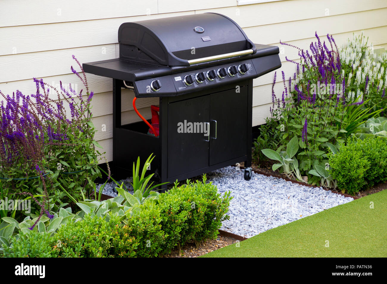 Grillplatz zwischen Blumenrabatten neben dem Golf Putting Rasen gelegen Stockfoto