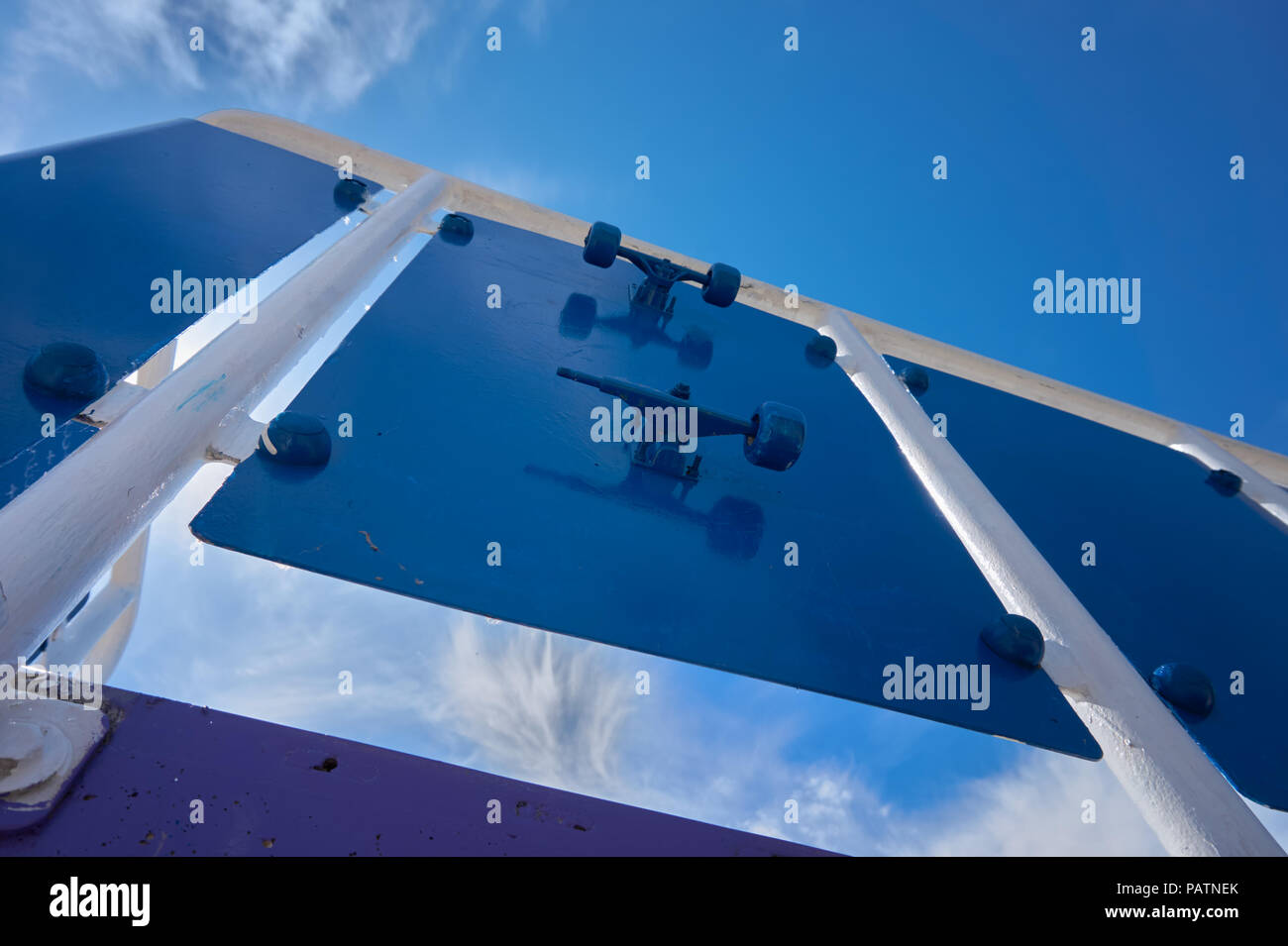Low Angle View auf Blau metall Wand mit Objekten heraus zwischen Weiß lackiert Polen unter blauen Himmel Stockfoto
