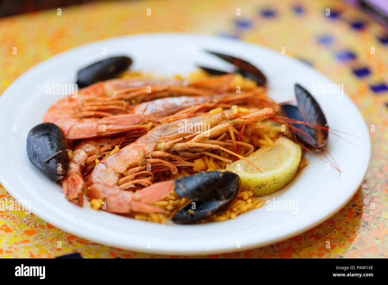 Royal Paella. Lecker Reis mit Garnelen, Muscheln und Zitrone auf weiße Platte Stockfoto