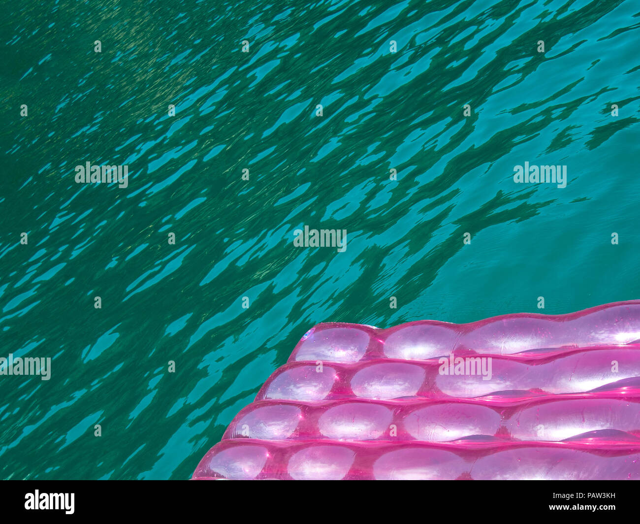 Detail einer rosa Aufblasbare Pad (Matratze) mit Wassertropfen auf der Oberfläche schwimmt im Meer Wasser blau grün transparent Stockfoto