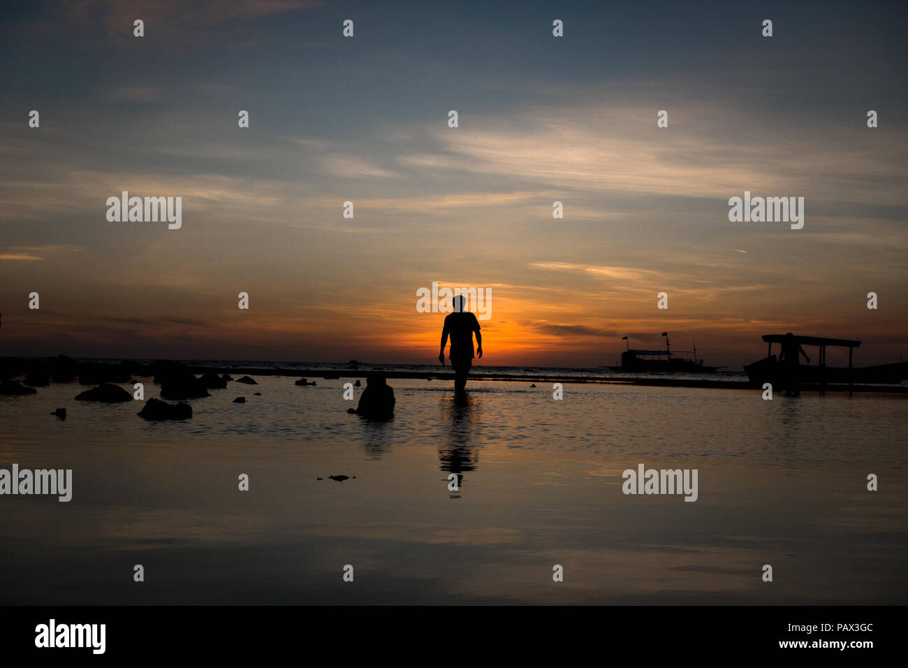 Silhouette der einsame Mann zu Fuß entlang des Wassers während der Ebbe Insel Sonnenuntergang - Cebu Malapascua - Philippinen Stockfoto