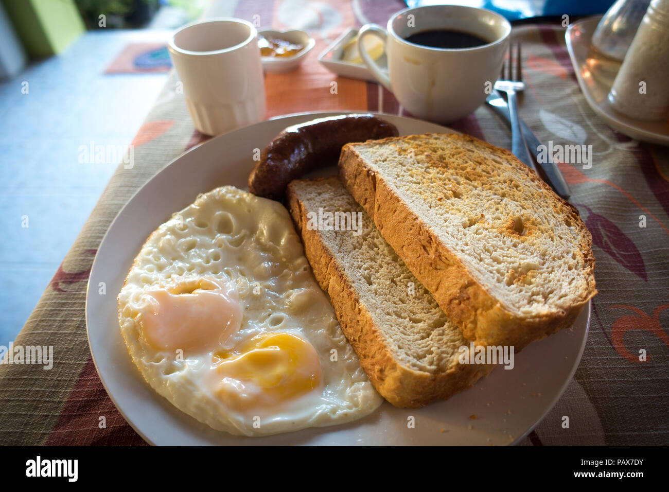 Frische resort Frühstück mit Kaffee, Spiegeleier, Würstchen und Brot auf dem Teller - Port Barton, Palawan - Philippinen Stockfoto