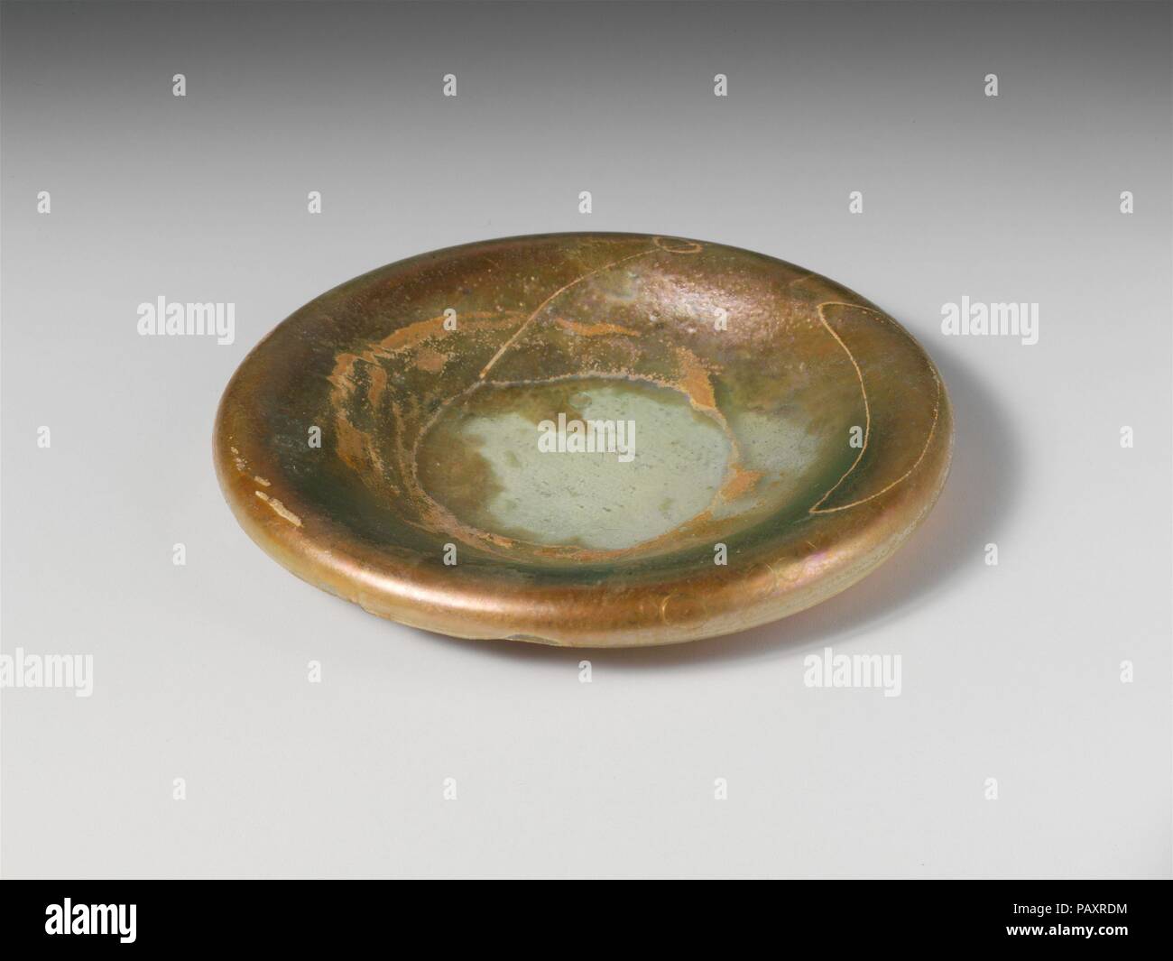 Glas Deckel. Kultur: Roman, der Zyprischen. Abmessungen: 1/2 in. (1,3 cm) Durchmesser: 3 cm. (8,3 cm). Datum: 2.-3.Jh. N.CHR.. Farblos mit grünlichen Farbton. Klopfte, invertiert Lippe; abgerundete Kante; breit, konkav nach oben. Intakt; Nadelstich und große Blasen; Patches von schwarzem Emaille Verwitterung und brillante Schillern auf der Innenseite; Mattierung und Schillern im Außenbereich. Museum: Metropolitan Museum of Art, New York, USA. Stockfoto