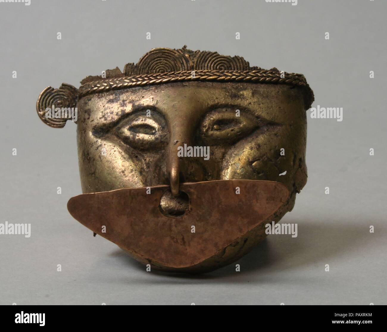 Anthropomorphen Kopf Anhänger. Kultur: zenú. Abmessungen: H.2 x W. 1 3/4 in. (5,1 x 4,4 cm). Datum: A.D.1-1000. Dieser hohle Metall Anhänger ist in der Form eines menschlichen Kopfes. Es war in erster Linie durch verloren - Wachs gießen gemacht. Die Person in der Anhänger dargestellt trägt eine Nase Ornament, ein separates dreieckigen Stück Blech. Die Besetzung Kopf erscheint, Gold oder wahrscheinlich ein gold Legierung mit Kupfer, während die rosa Farbton der Nase ornament schlägt vor, sie hat eine höhere Kupfergehalt. Ein casting Kern aus Keramik anwesend wäre, haben sich in den Raum des hohlen Inneren gewesen; es war fast völlig nach Th entfernt Stockfoto