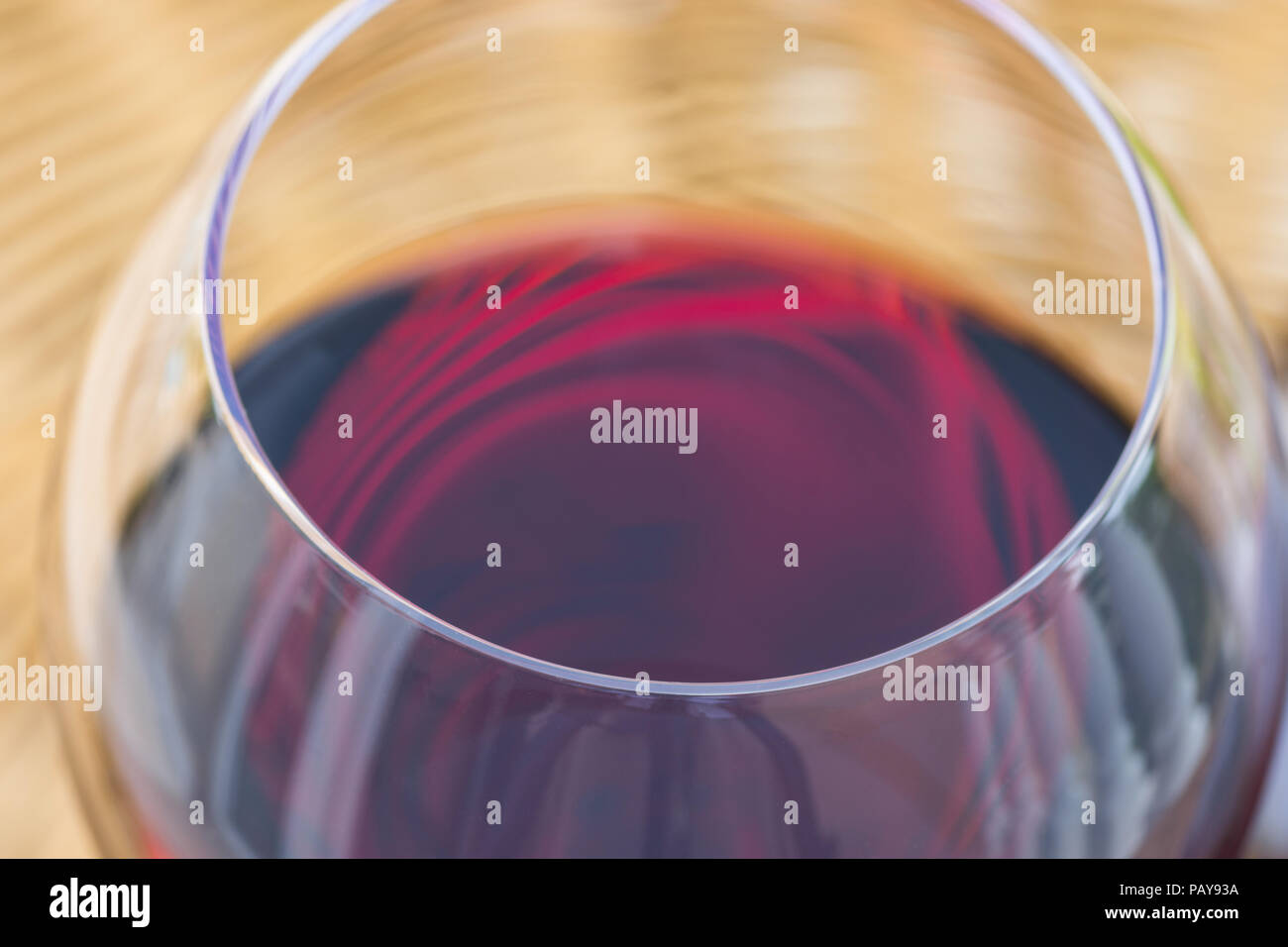 Nahaufnahme Makro von Glas Rotwein auf Rattan Rattan Tisch im Garten Terrasse von Villa oder Landhaus. Authentischen Lebensstil Bild. Entspannung Genuss Gou Stockfoto