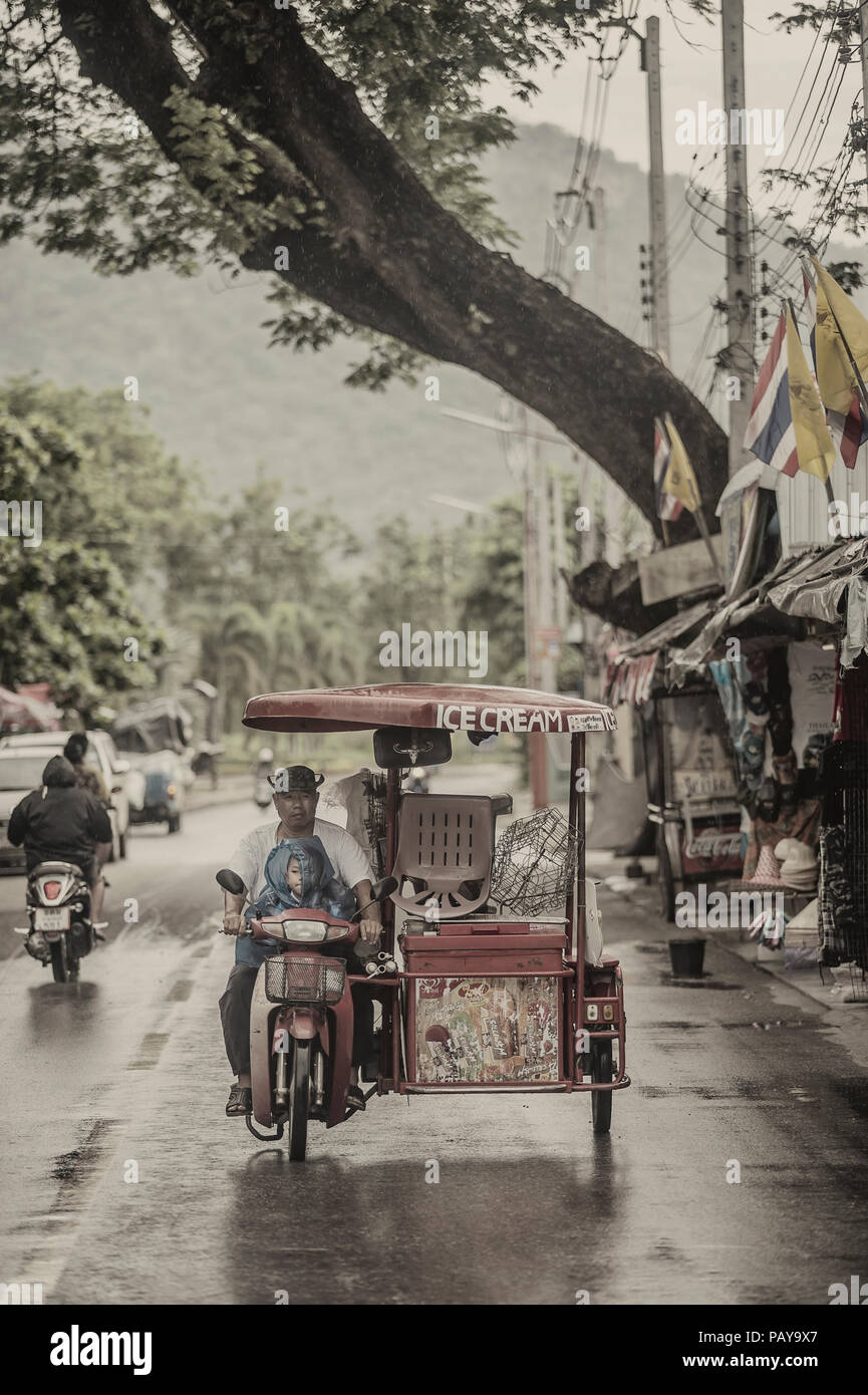 Eis Verkäufer mit einem Kind, einem motorisierten Dreirad im Regen Kanchanaburi Thailand Stockfoto