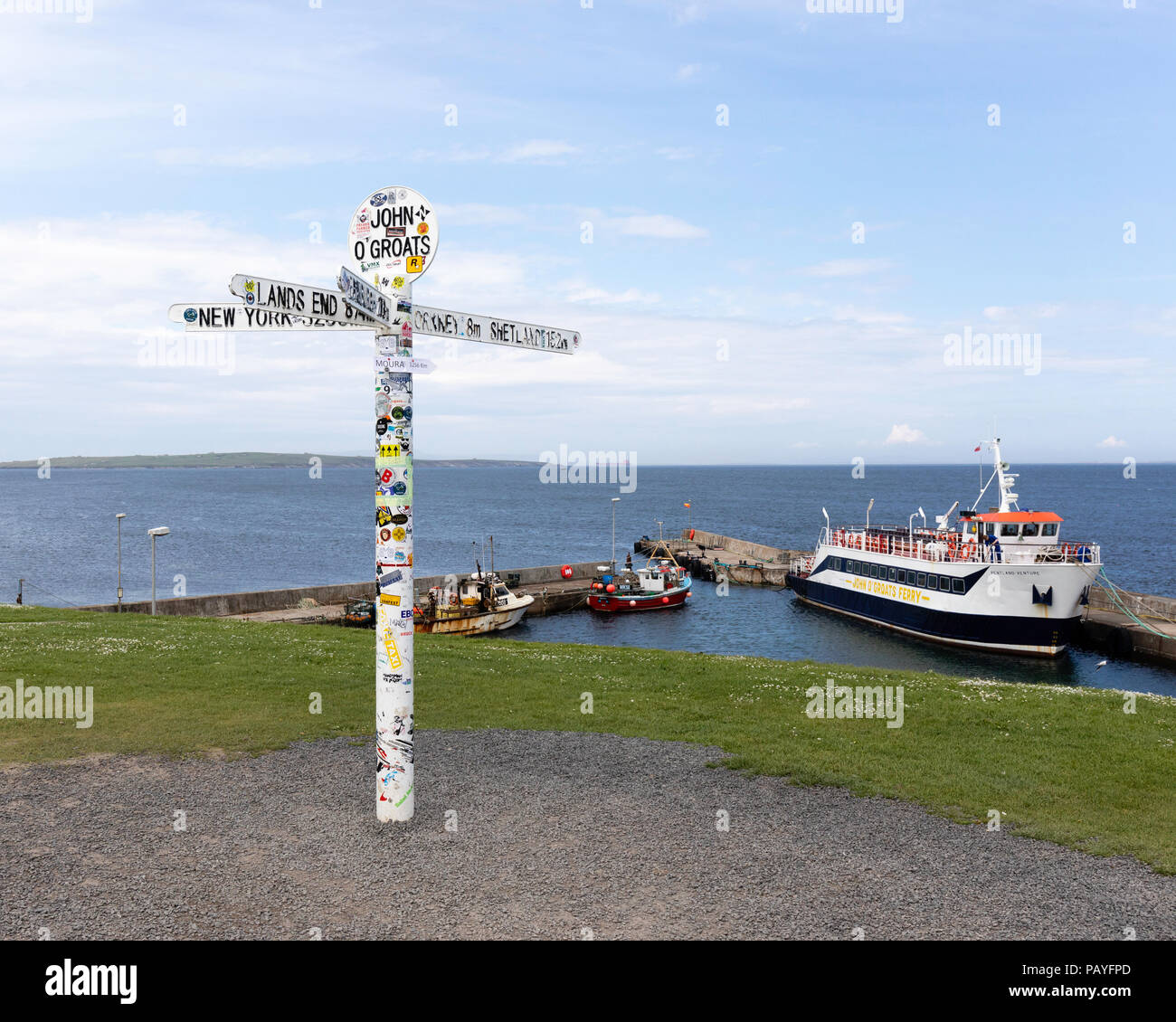 Der Schild zeigt das Ende der Straße an der John O' Groats mit dem Hafen, Fähre und Orkeney im Hintergrund Stockfoto