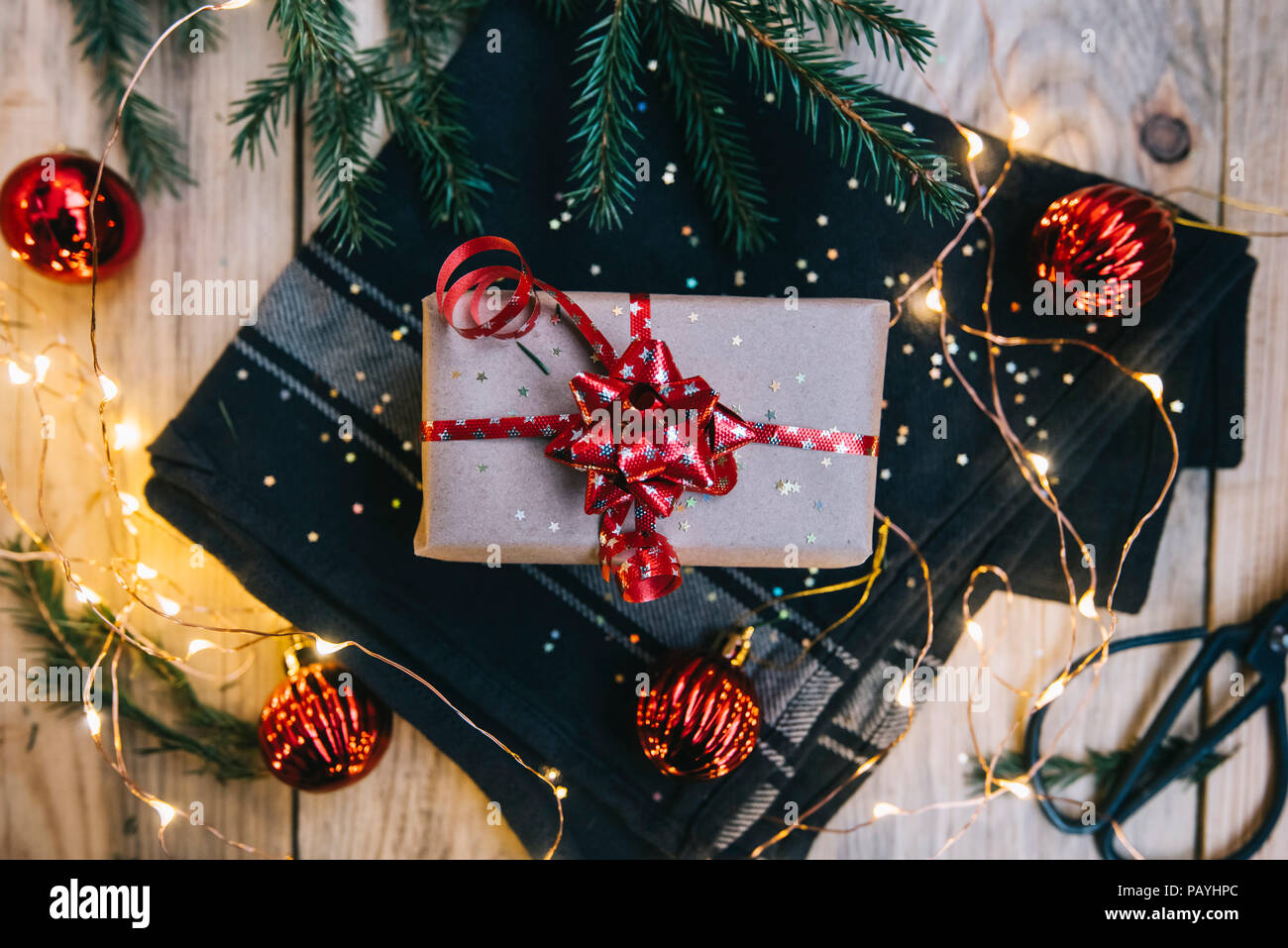 Verpackung der Geschenke Essentials auf der rustikalen Holztisch Hintergrund. Weihnachtsgeschenk, kiefer Blätter, Glühwürmchen, Funken, Handwerk Schere und Weihnachtsdekor Stockfoto