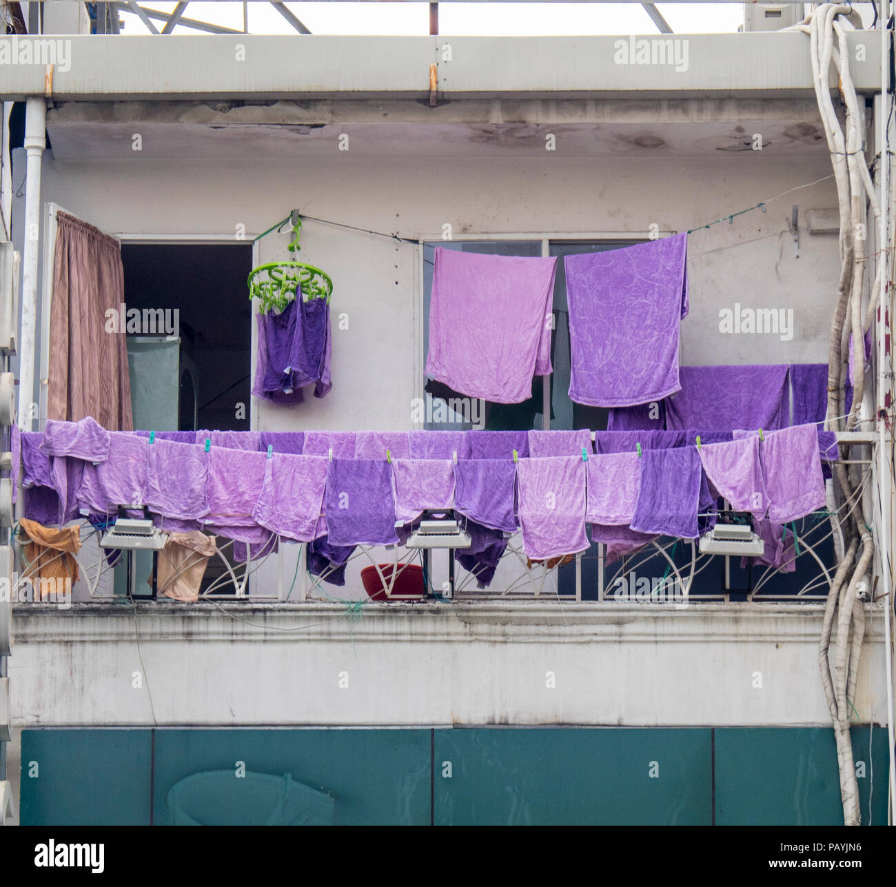 Lila Handtücher hängen an einer Wäscheleine auf einem Balkon eines Gebäudes in Ho Chi Minh City, Vietnam zu trocknen. Stockfoto