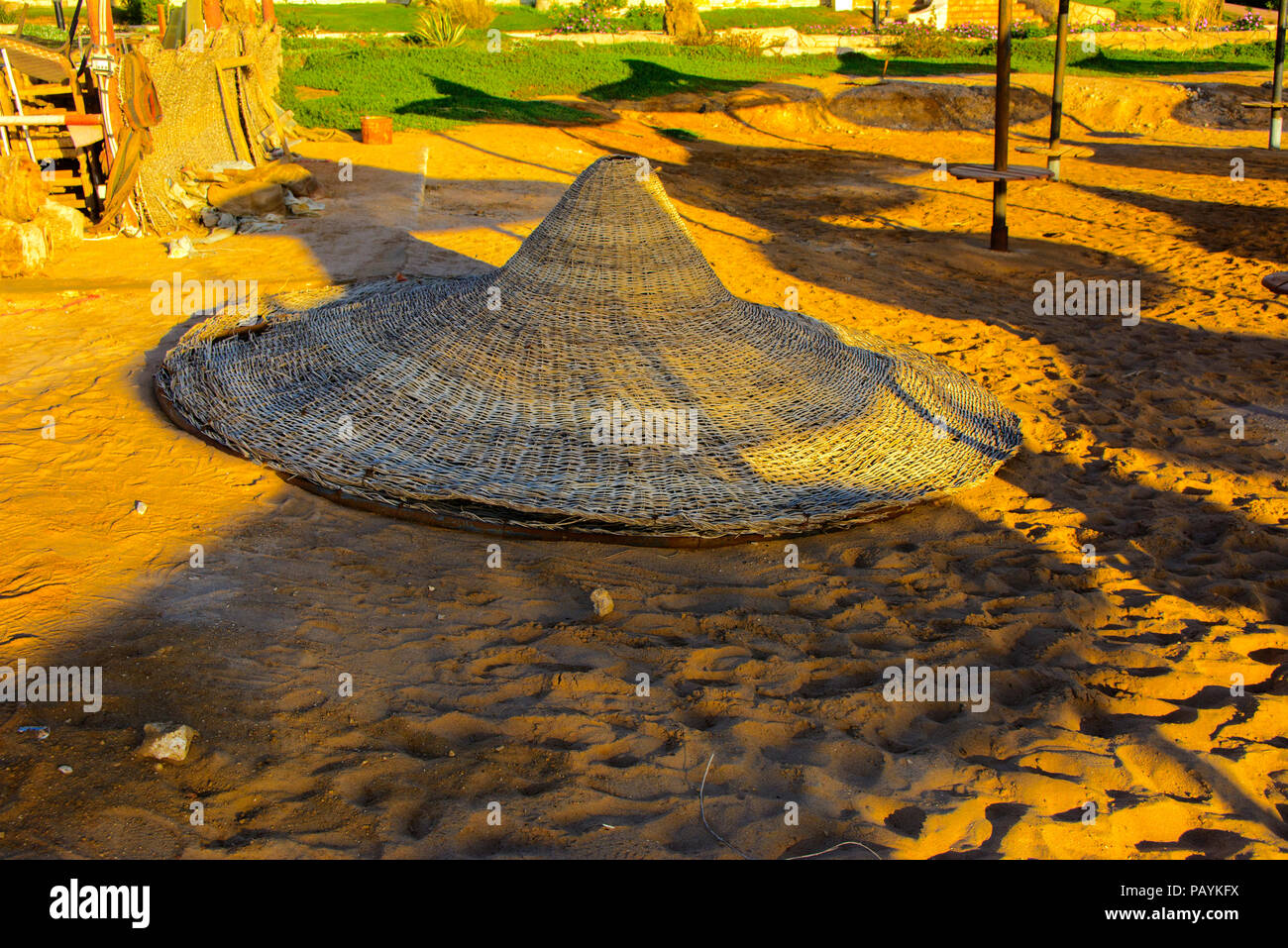 Eine Reihe von Stroh Sonnenschirme gegen Überhitzung und Sonnenliegen am Strand vor einem blauen Himmel und das blaue Meer zu schützen. Das Konzept der Sommerferien, Stockfoto