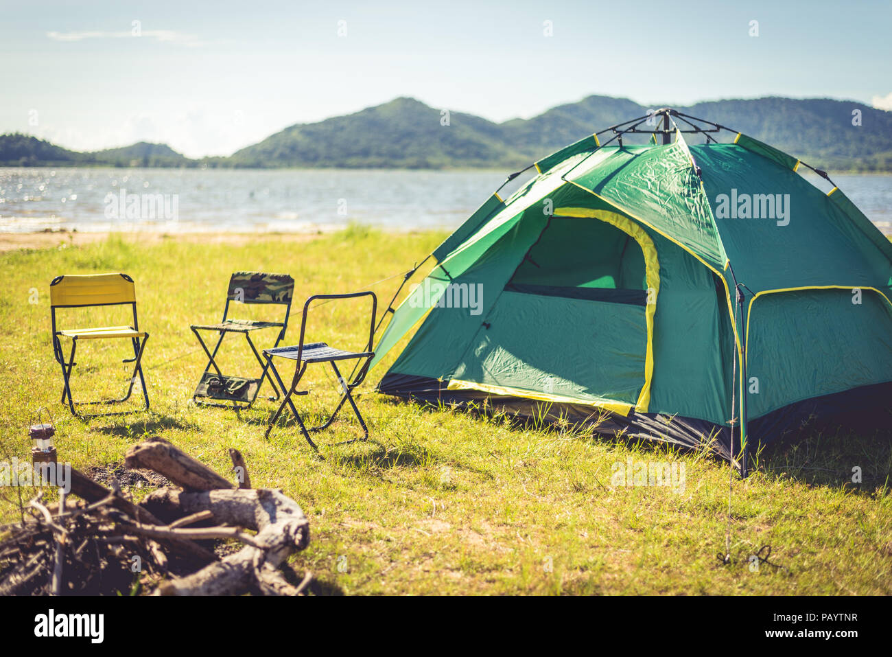 Camping Zelt mit gelöscht Lagerfeuer im grünen Feld Wiese Camping Zelten auf grünen Wiesen neben Meer beleuchtet von