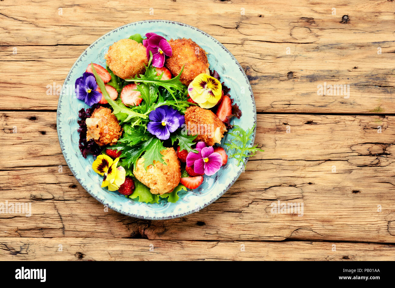 Vitamin Sommer Salat mit Erdbeeren, gegrillten Käse, Rucola und Blumen. Gesundes Essen Stockfoto