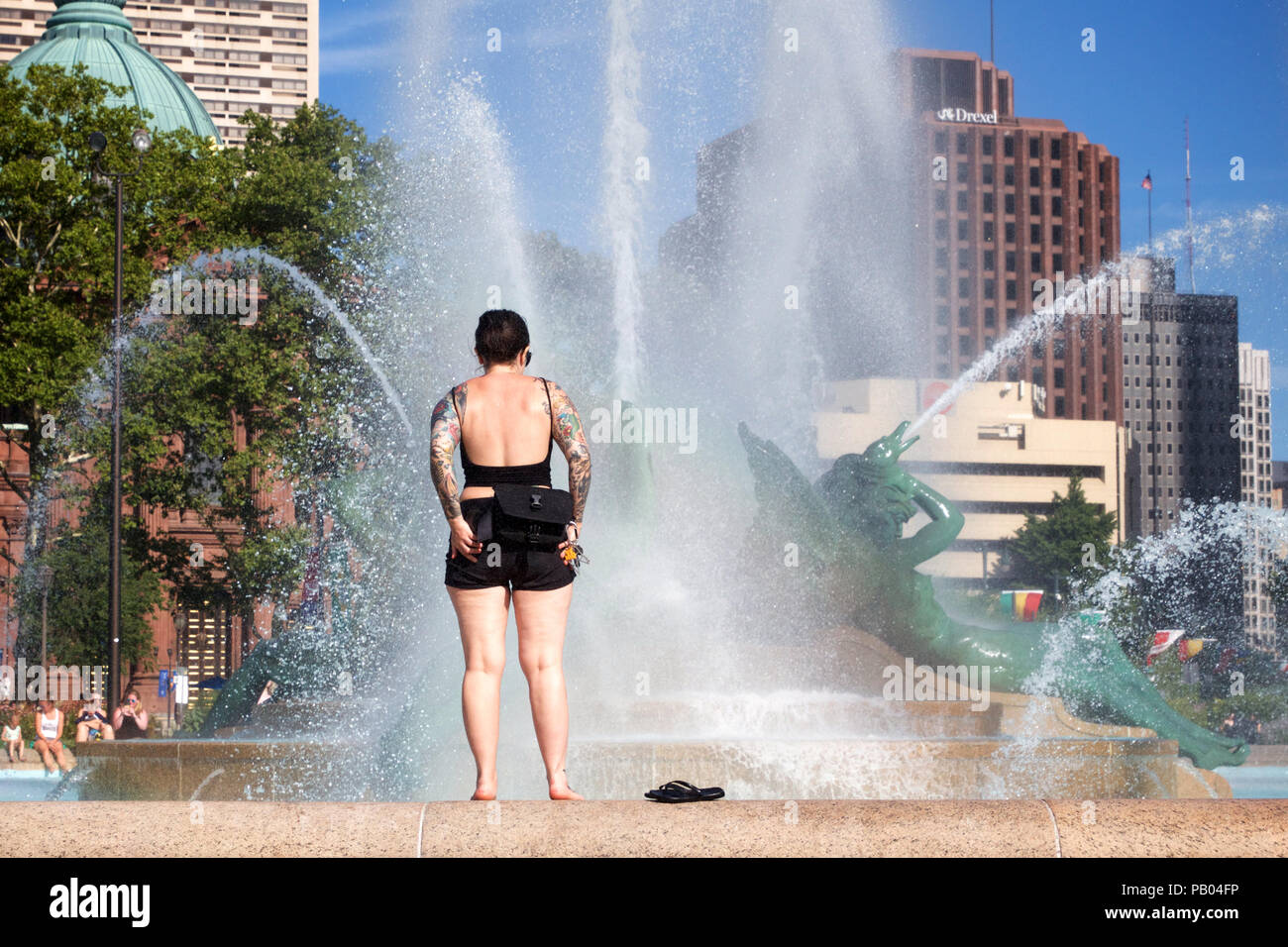 Philadelphia, PA USA - Juli 20, 2018: eine junge Frau in den Tätowierungen bedeckt bereitet im Swann Memorial Fountain bei Logan Circle, Philadelphia zu waten. Stockfoto