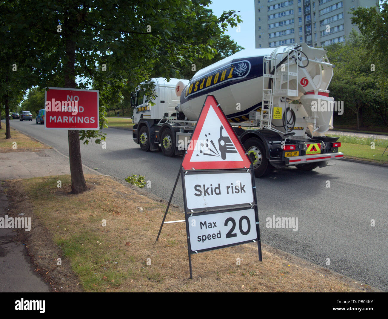 Betonmischer Lkw vorbei an Schildern skid Risiko max Speed 20 und keine Fahrbahnmarkierungen Stockfoto