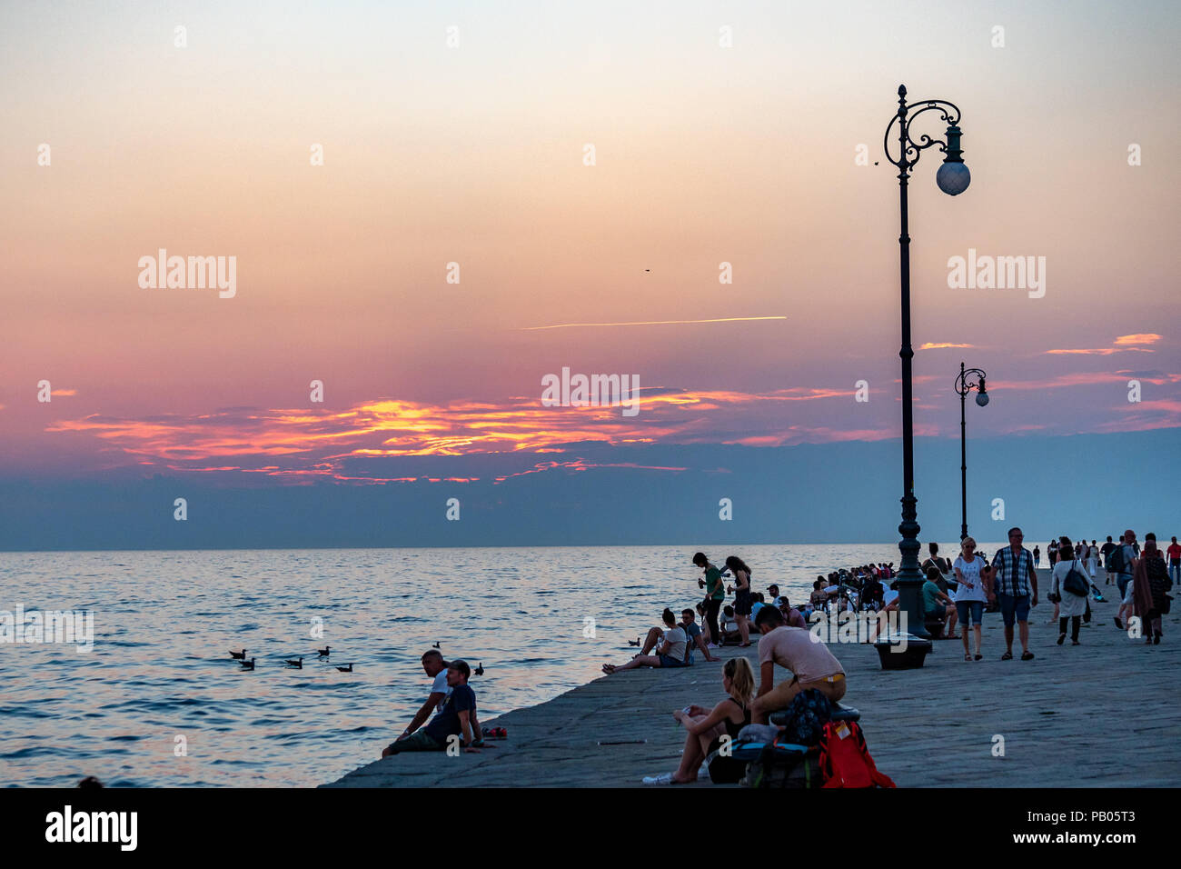 Triest, Italien, vom 25. Juli 2018. Die Menschen genießen den Sonnenuntergang von der ikonischen Molo Audace (Audace Pier) in der norditalienischen Stadt Triest. Die 246-Mete Stockfoto