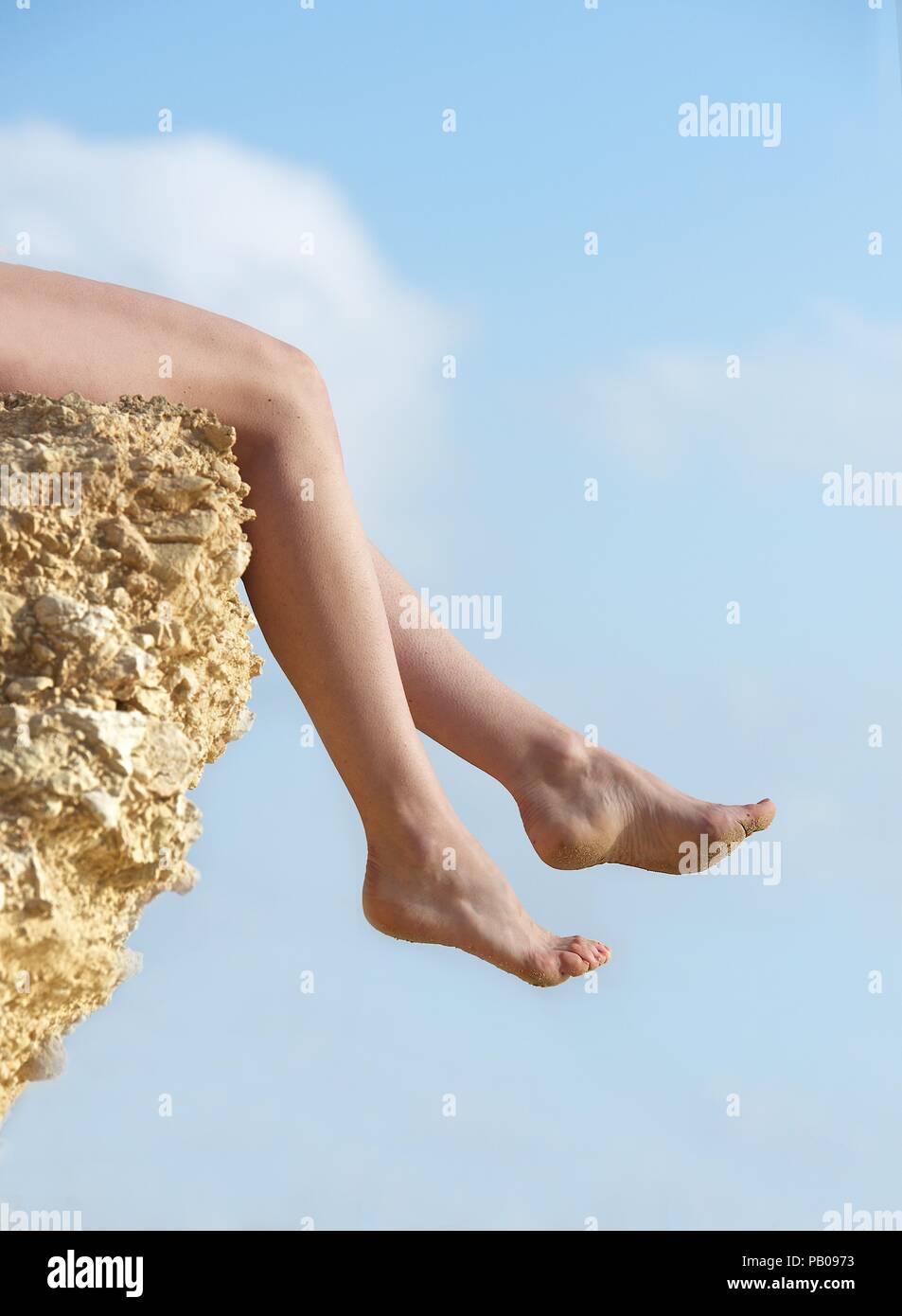 Woman's Beine über den Rand eines Rock baumelt. Stockfoto
