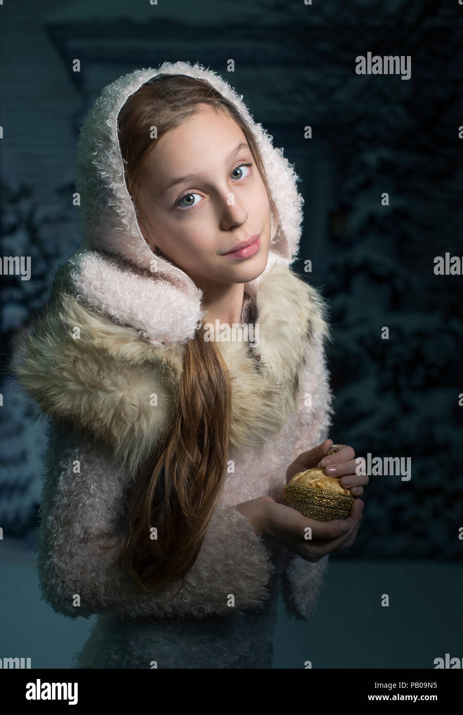 Portrait von ein stehendes Mädchen im Schnee mit einem goldenen Christbaumkugel Stockfoto