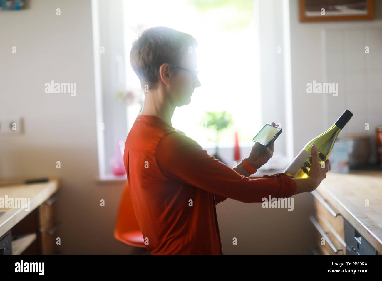 Frau detailliert prüfen eine Flasche Wein auf Ihrem Mobiltelefon Stockfoto