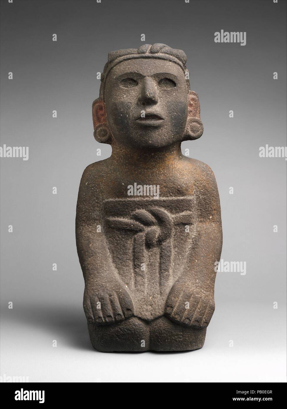 Kniende weibliche Figur. Kultur: Aztec. Abmessungen: Insgesamt: 21 1/2 x 10 1/2 in. (54,61 x 26,67 cm) Andere: 10 1/2 in. (26,67 cm). Datum: 15. Anfang des 16. Jahrhunderts. Aztekischen Bildhauer verwendet, um bestimmte formale und ästhetische Konventionen die menschliche Figur darzustellen. Sitzenden weiblichen Figuren sind in der Regel mit ihren Beinen unter ihnen versteckt dargestellt, ihre Füße nach innen gedreht, so dass in den Rücken, ihre Zehen berühren. Ihre Hände ruhen auf den Knien. Diese Skulptur zeigt eine elegante Aztec dame trägt eine kurze, einfache Rock um die Taille mit einem Gürtel geknotet in Flachrelief gearbeitet befestigt. Sie trägt keine obere Alimcj Stockfoto