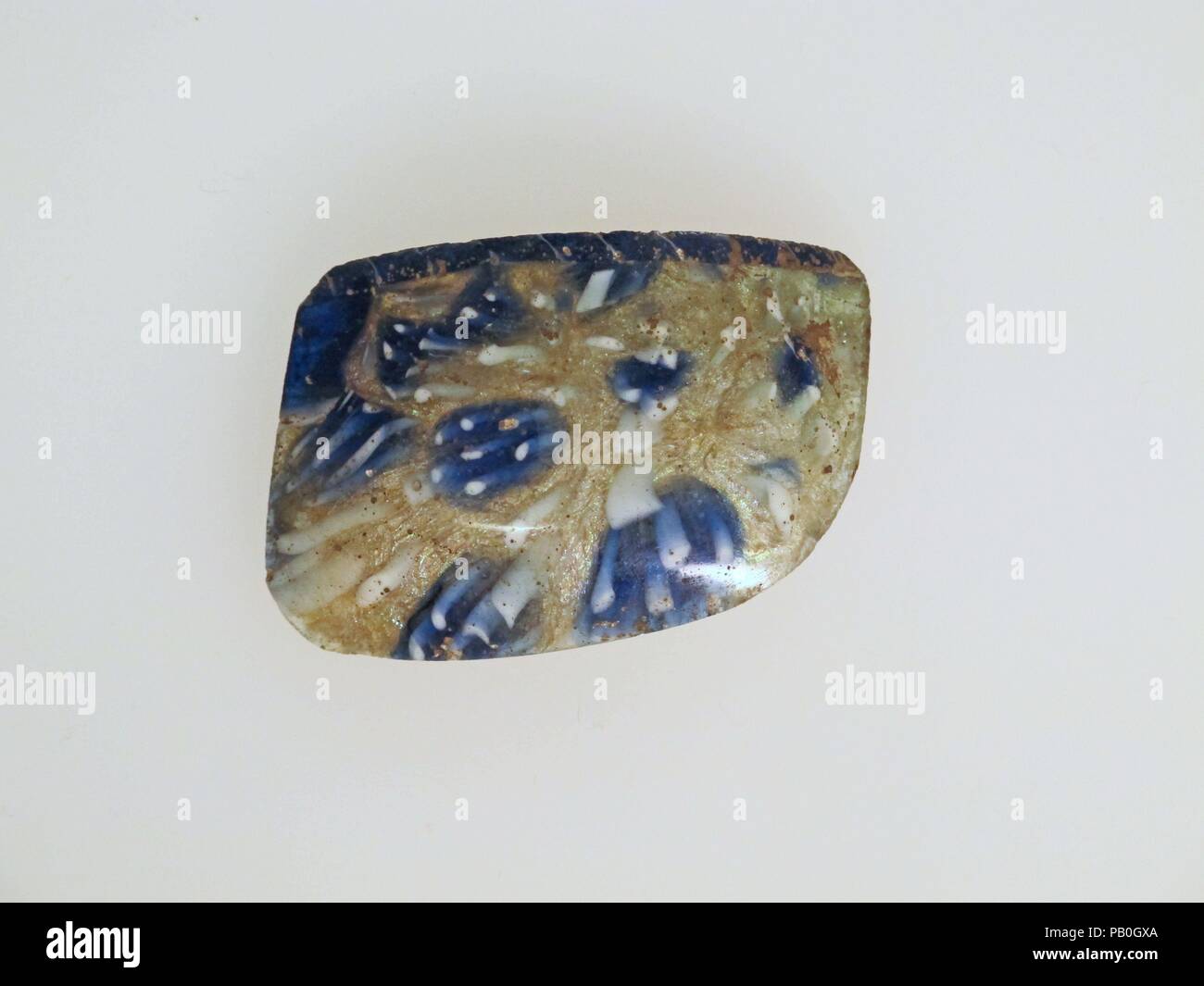 Glas Mosaik Schüssel Fragment. Kultur: Roman. Abmessungen: 1 1/4 x 1 13/16 × 1/8 in. (3,1 × 4,6 × 0,3 cm) geschätzten Durchmesser: 3 1/8 in. (8 cm). Datum: Ende 1.Jh. v. Chr. - frühe 1. Jh. N.CHR.. Transluzente Kobaltblau, Deckweiß, und farblos mit bläulichen Farbton. Vertikale Felge mit flache Dichtlippe; fast vertikale Seite, sanft nach innen, dann gebogen deutlich nach unten. Composite Mosaik Muster aus den Abschnitten eines einzigen Stock in eine farblose Masse mit unregelmäßigen weißen Stangen Umgebung ein blauer Kreis mit weißen Stangen gebildet. Eine große blaue Netzwerk Zuckerrohr würde spiralförmig mit einem weißen Faden wird Stockfoto