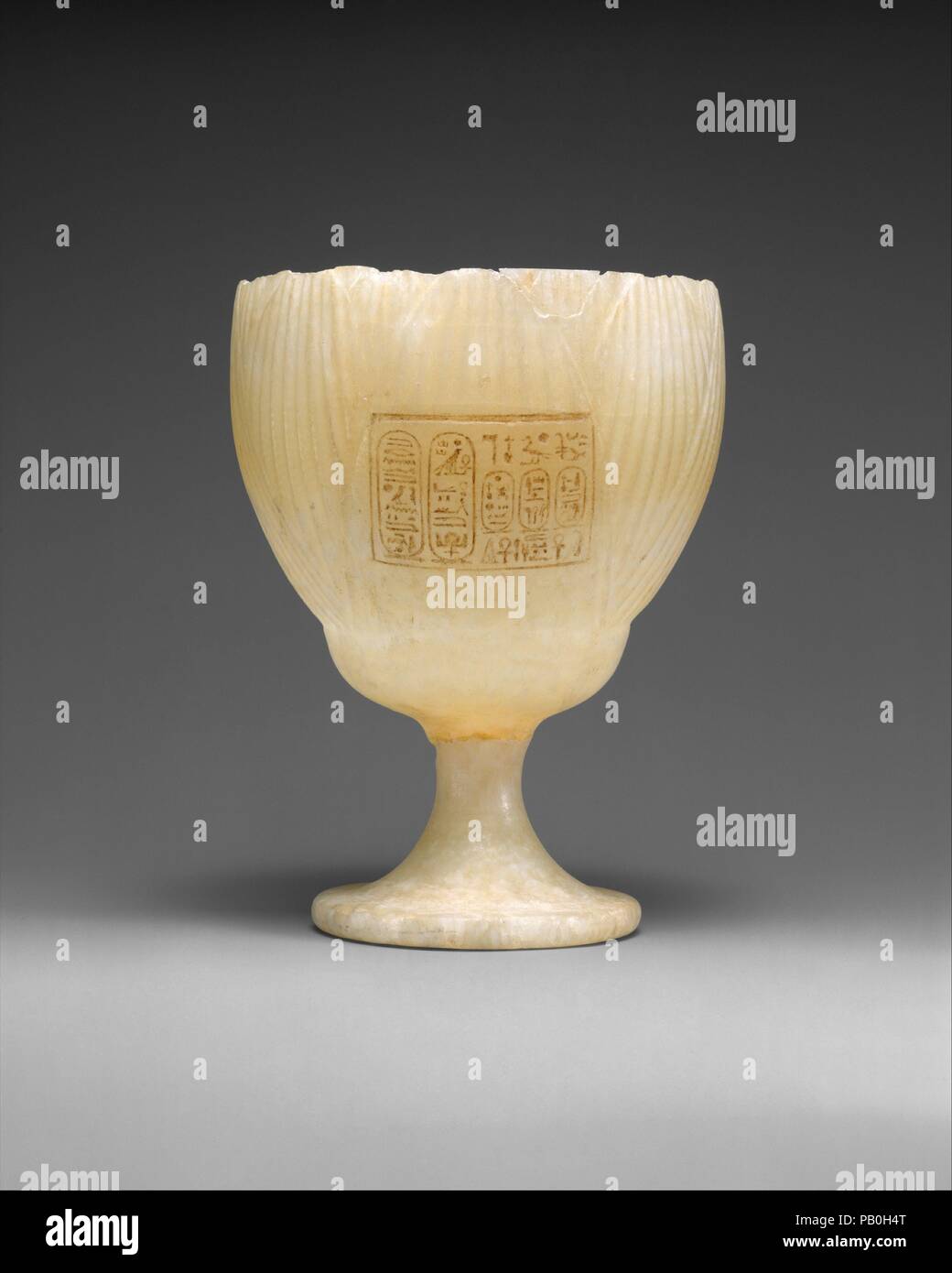 Becher beschriftet mit den Namen von König Amenophis IV. und Königin Nofretete. Abmessungen: H.14 (5 1/2 in.); Durchm. 10,5 cm (4 1/8 in.). Dynastie: Dynasty 18. Herrschaft: Herrschaft von Echnaton. Datum: Ca. 1353-1336 v. Chr.. Diesen anmutigen, transparente Trinkbecher in Form einer weißen Lotus Blossom ist geschätzt, sowohl für seine Schönheit und seine historischen Interesse. Das Nomen (persönliche Name) und Prenomen (Thron) Amenophis IV. in der kleinen Leiste auf der Seite eingeschrieben sind, zwischen zwei Kartuschen, die die frühen Titularen der Aten (links) und einer Kartusche der Benennung der wichtigsten Königin Nofretete (rechts). Thu Stockfoto