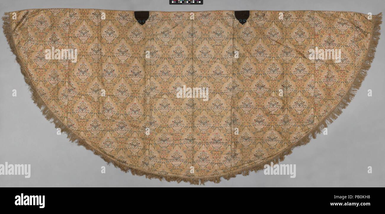 Fertig zu werden. Abmessungen: Textil: L. 57. (144,8 cm) W. 123 1/2 in. (313.7 cm) mit Fransen: L. 60 in. (152,4 cm) W. 126 1/2 in. (321.3 cm). Datum: Anfang des 17. Jahrhunderts. Dieses Kleidungsstück ist beispielhaft für den Einsatz von iranischen Textilien in ganz Europa. In der christlichen liturgischen Dienste getragen, es ist von mehreren Längen der Safawidischen luxus Seide geschmückt mit Metall verpackt Threads. Das Gitter Rahmen der beherbergt eine symmetrische Blumenstrauß aus Mohn und Tulpen um ein zentral gelegenes Iris in einer Vase. Weitere blumen Wind ihren Weg auf einem Foliate Weinstock in der Gitter auf einem goldenen gelb. Die Stockfoto