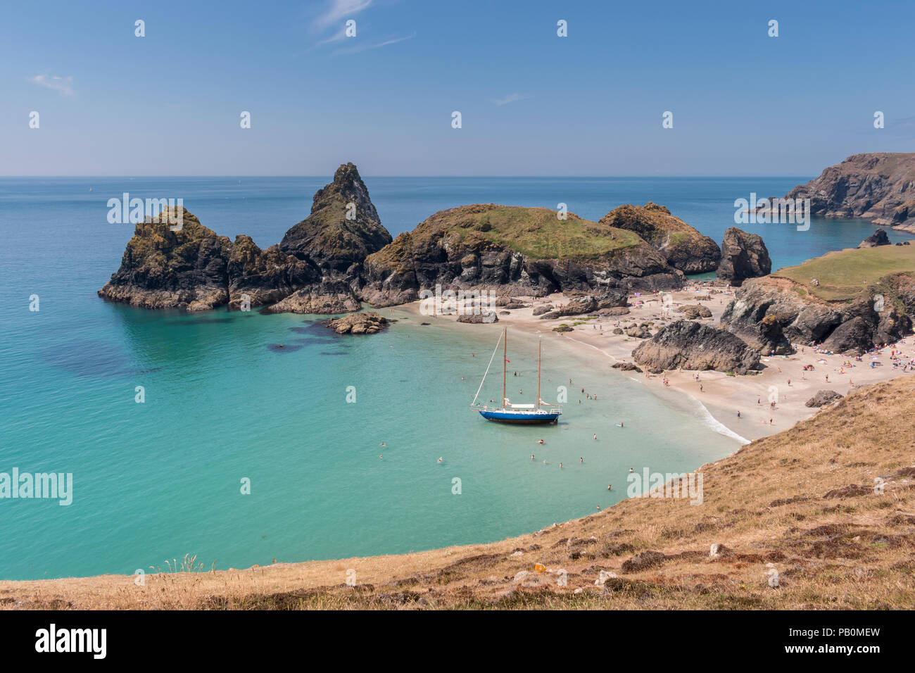 Sommer in Cornwall - Urlauber an Kynance Cove auf der Lizard Halbinsel paddeln Um eine Yacht Strände bei Ebbe, Großbritannien Stockfoto