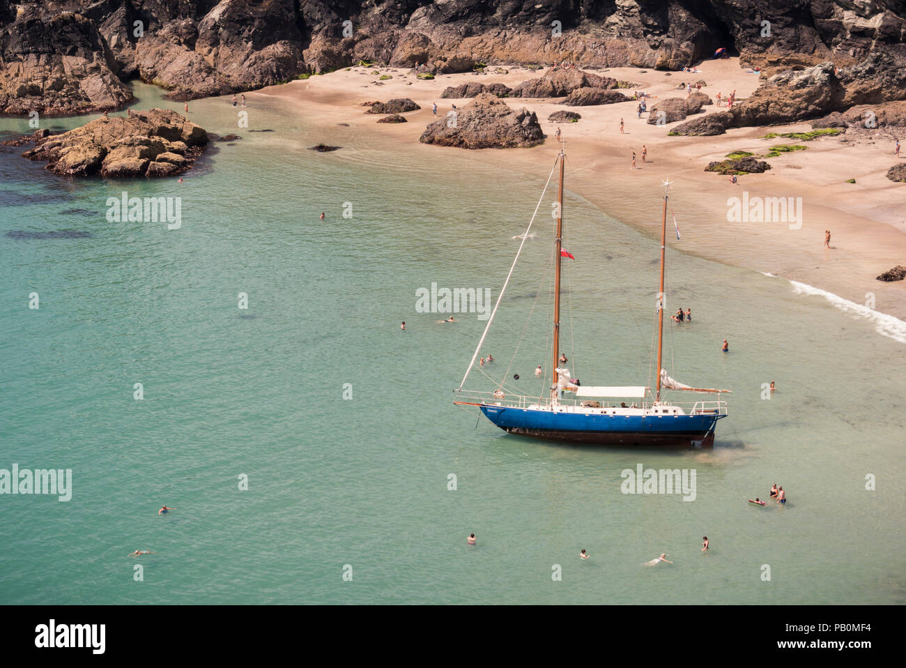 Sommer in Cornwall - Urlauber an Kynance Cove auf der Lizard Halbinsel paddeln Um eine Yacht Strände bei Ebbe, Großbritannien Stockfoto