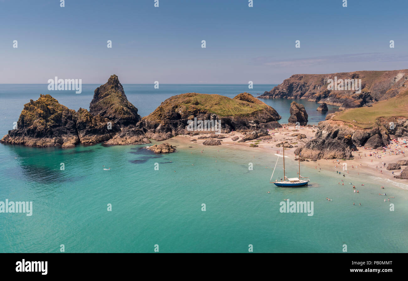 Sommer in Cornwall - Urlauber an Kynance Cove auf der Lizard Halbinsel paddeln Um eine Yacht Strände bei Ebbe, Großbritannien Stockfoto