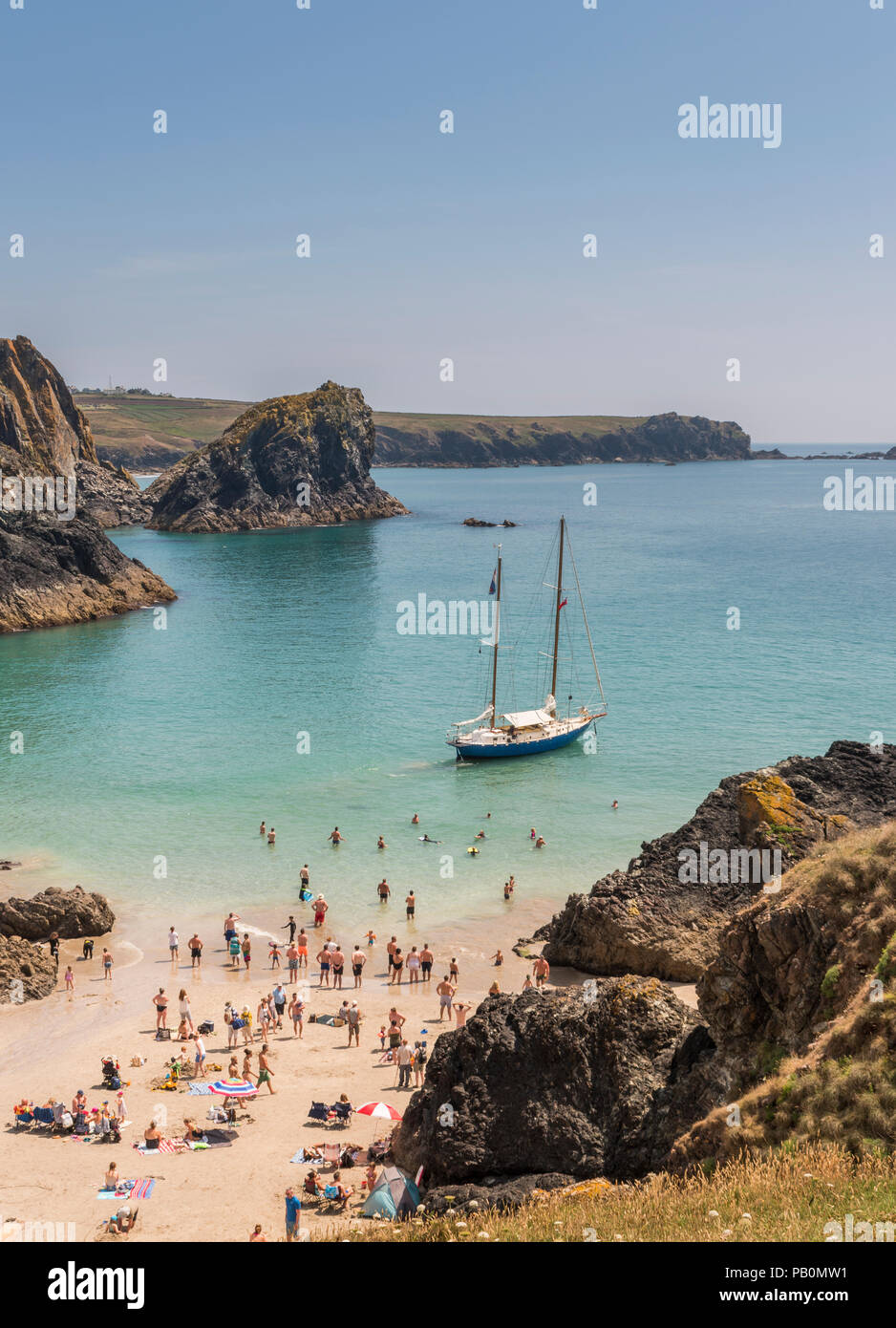 Sommer in Cornwall - Urlauber an Kynance Cove auf der Lizard Halbinsel paddeln Um eine Yacht Strände bei Ebbe, Großbritannien Stockfoto